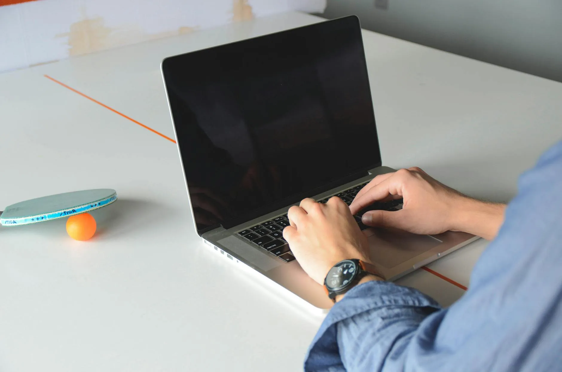 Close-up of student's hands typing notes on a tablet amidst a messy dorm desk, simulating study methods.