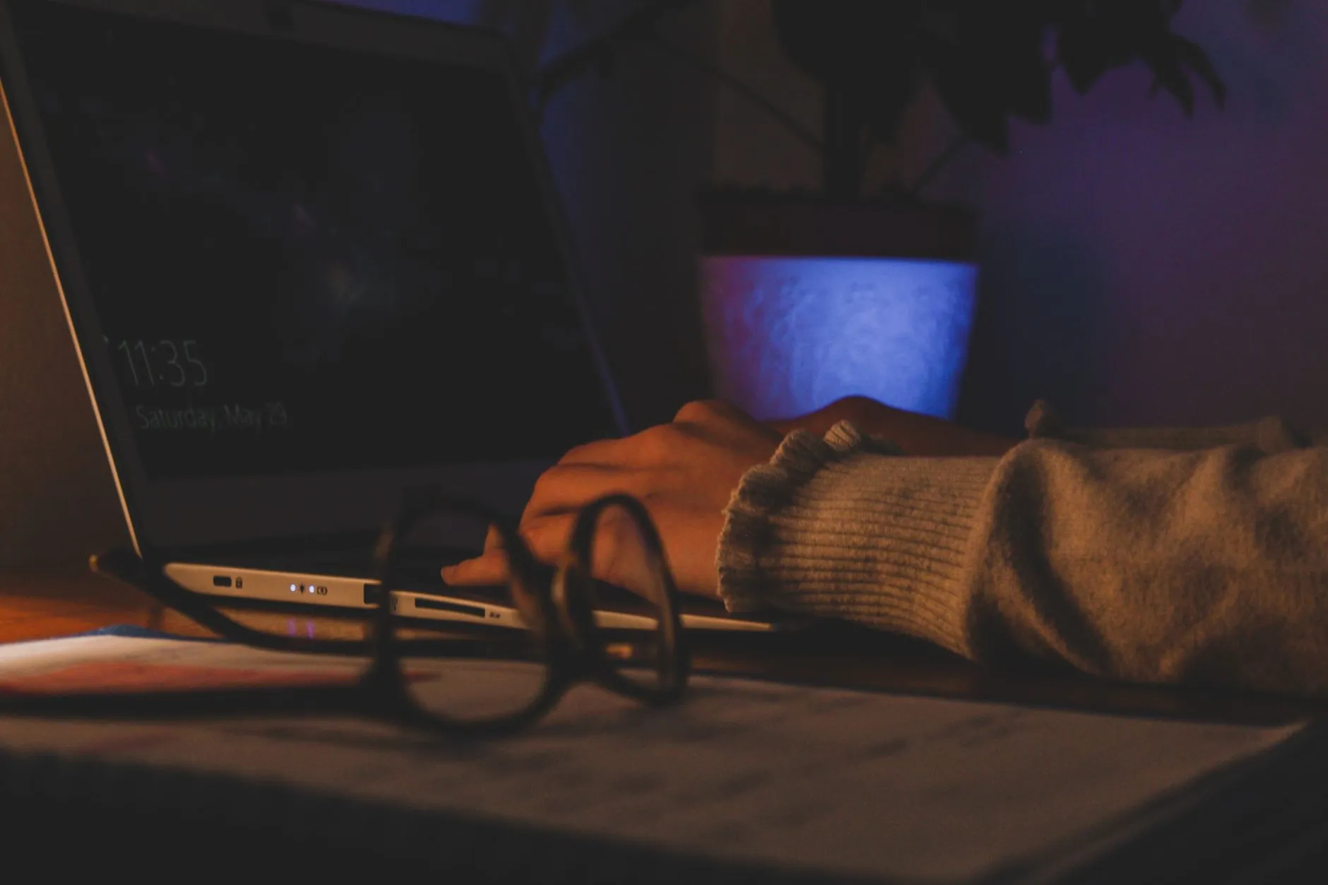 Close up of hands typing on a laptop with lecture slides open on a messy dorm desk
