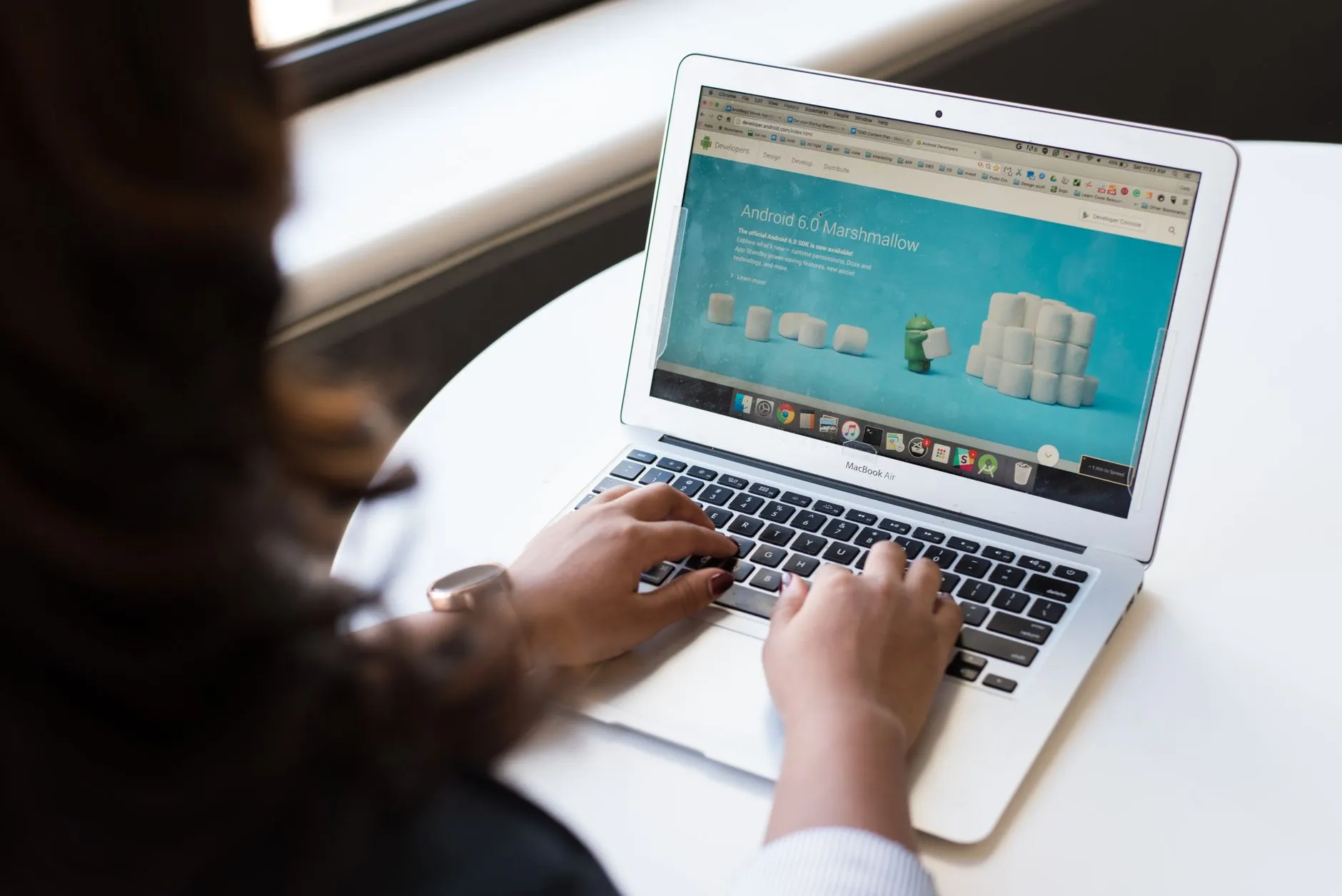 Close up of hands typing on a laptop keyboard with lecture slides open on the screen
