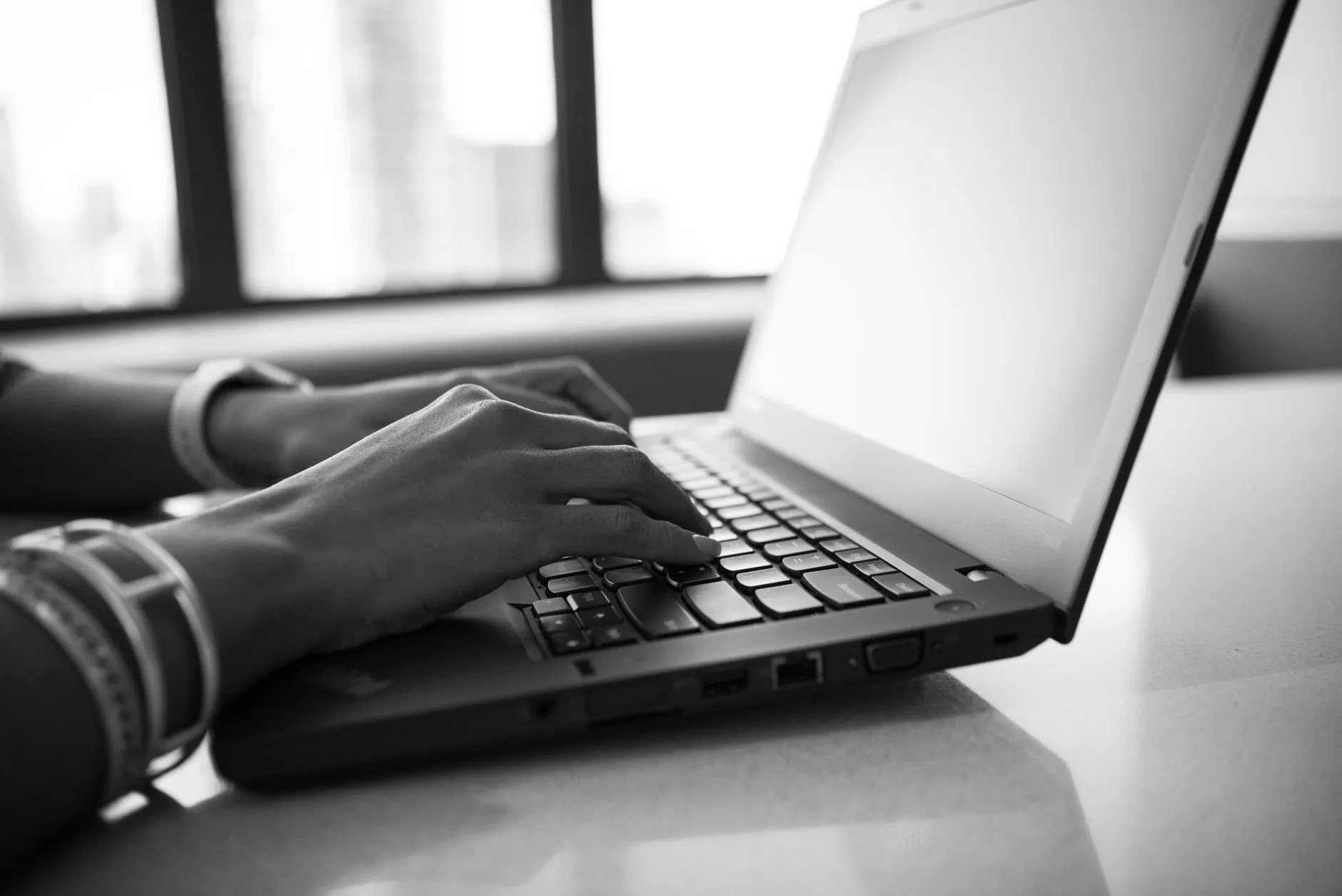 Close up of a student's hands typing on a laptop on a messy dorm room desk