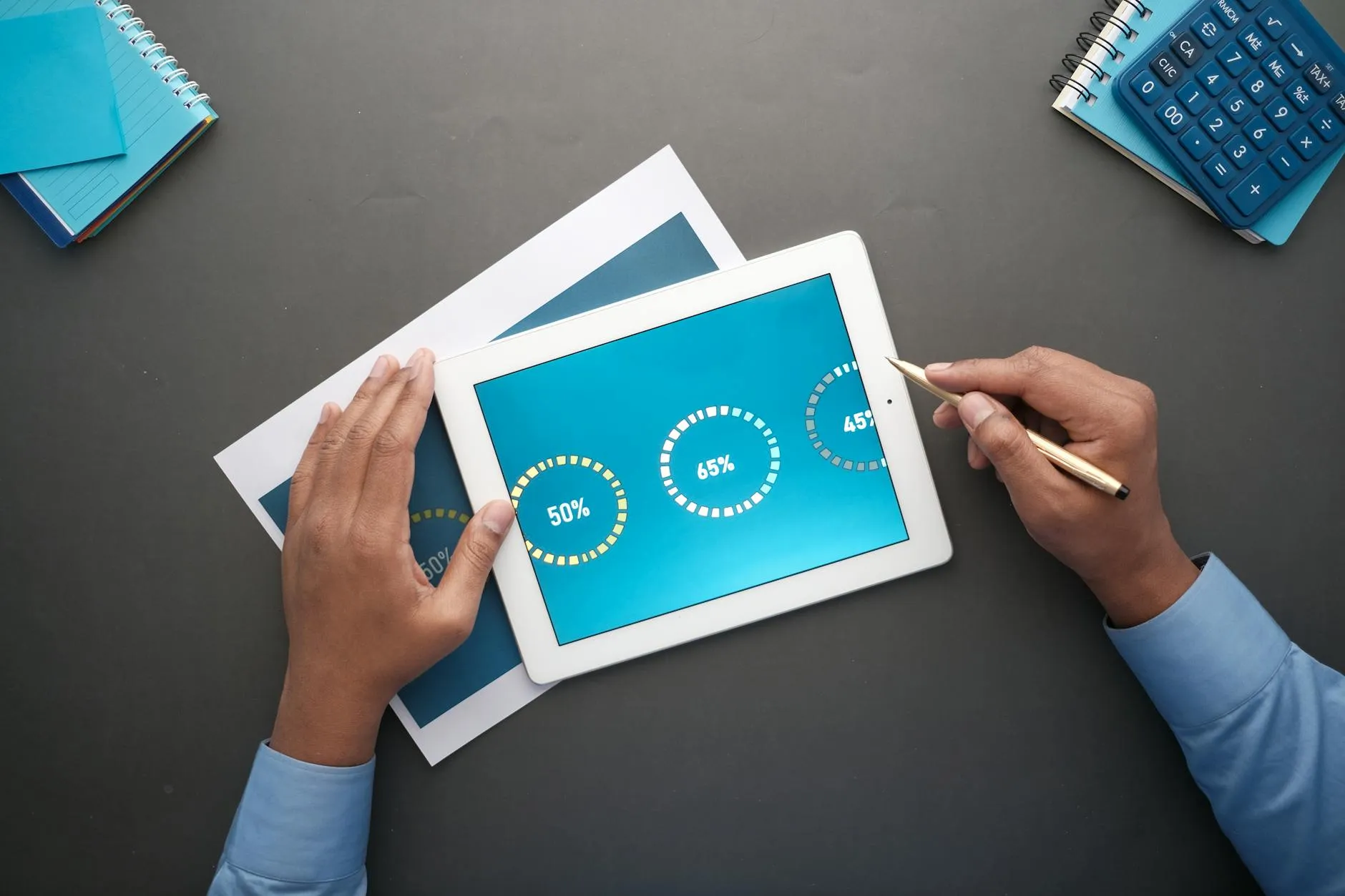 Close up of a students hands using a digital tablet for studying on a cluttered desk