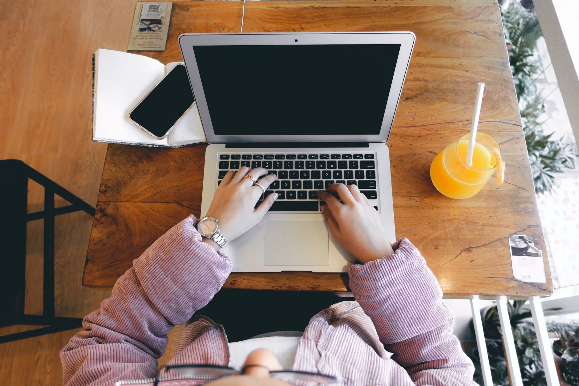 Close up of hands typing on a laptop on a messy student dorm desk with notebooks