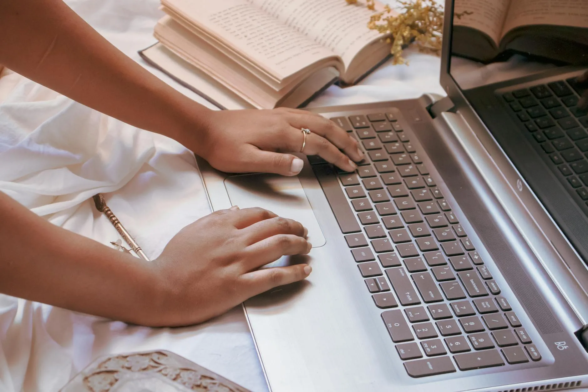 Close up of a student's hands interacting with a tablet screen showing study apps on a cluttered wooden desk