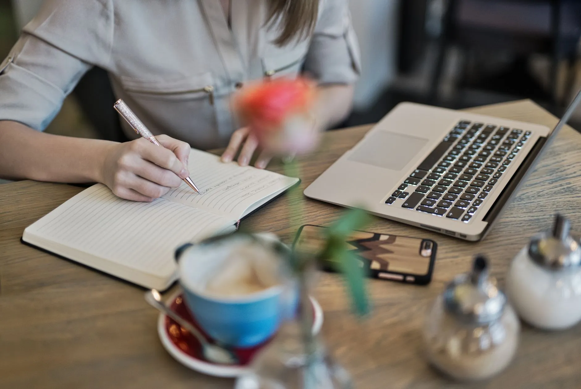 Close up shot of hands writing notes on a tablet in a cozy coffee shop with soft window light