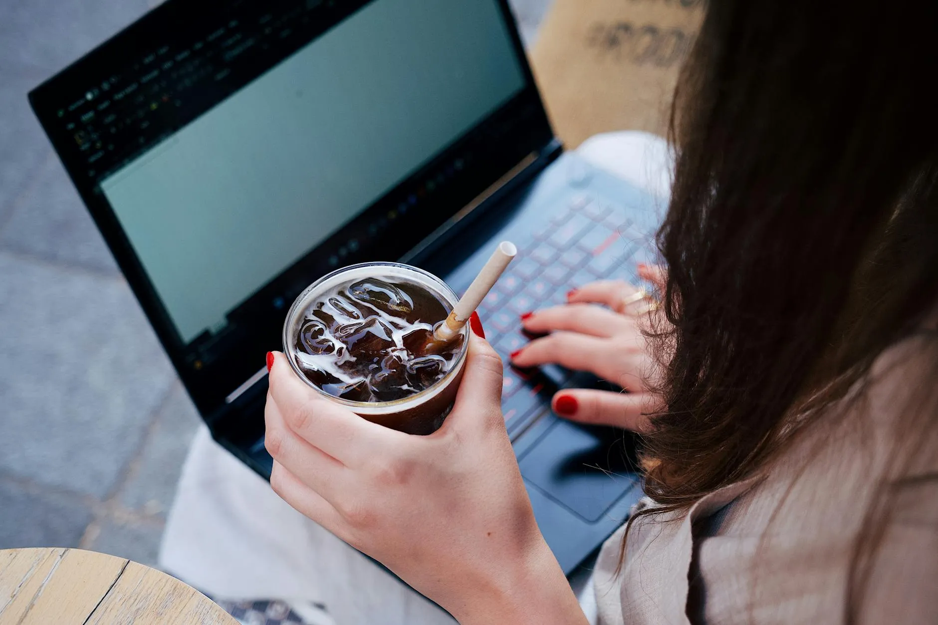 Close up of a student using a laptop in a busy campus coffee shop environment