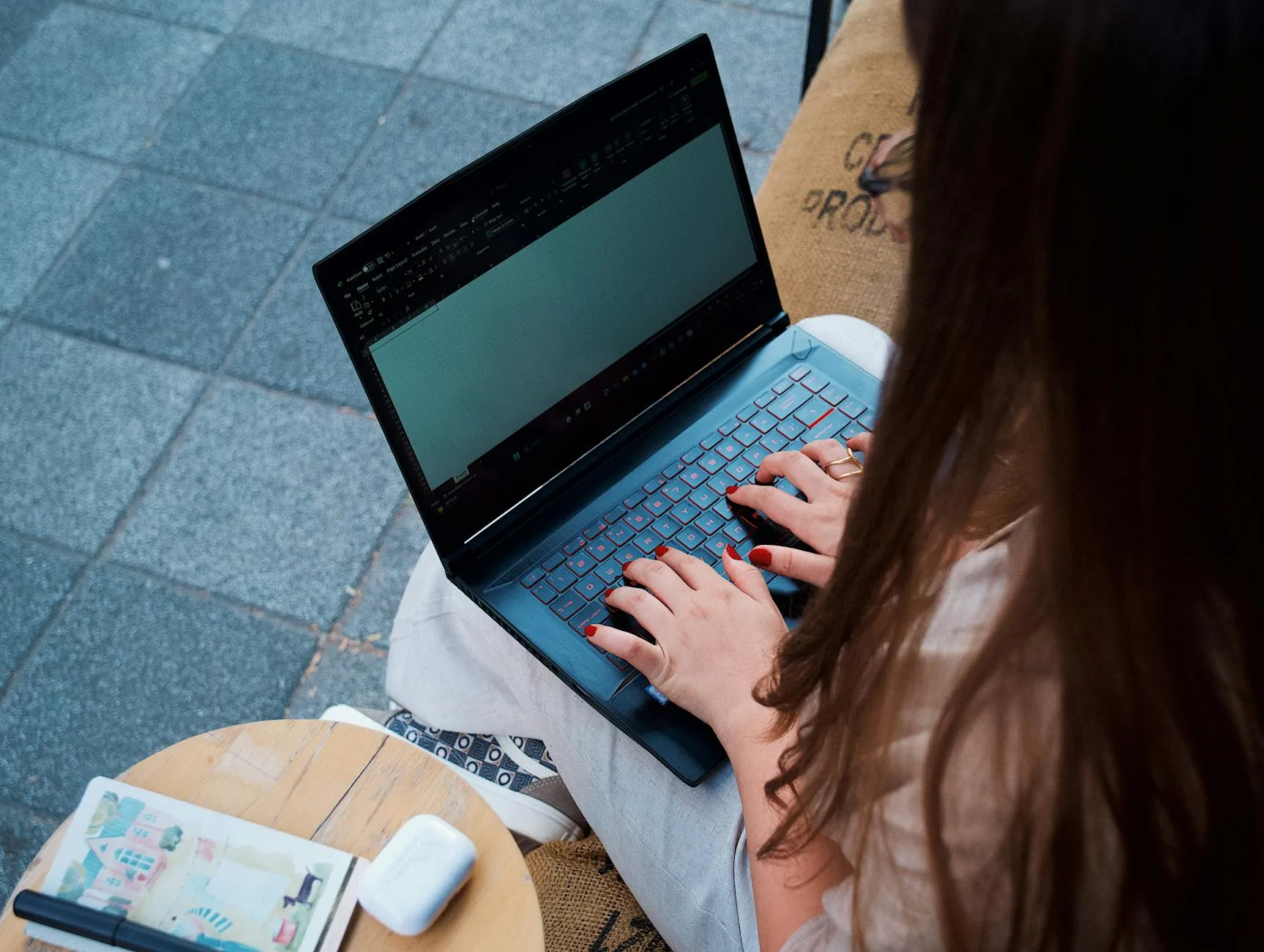 Detail shot of a student's hands typing on a laptop decorated with stickers next to a coffee cup