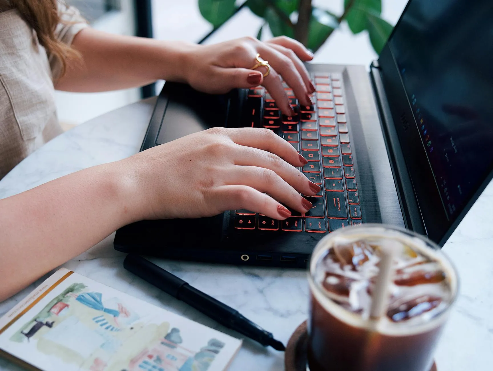 Detail shot of a student working on a laptop surrounded by study materials