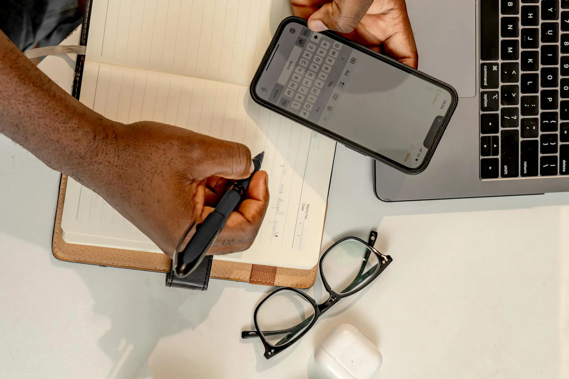Close-up of a student's hands typing on a laptop, surrounded by study materials in a dorm room