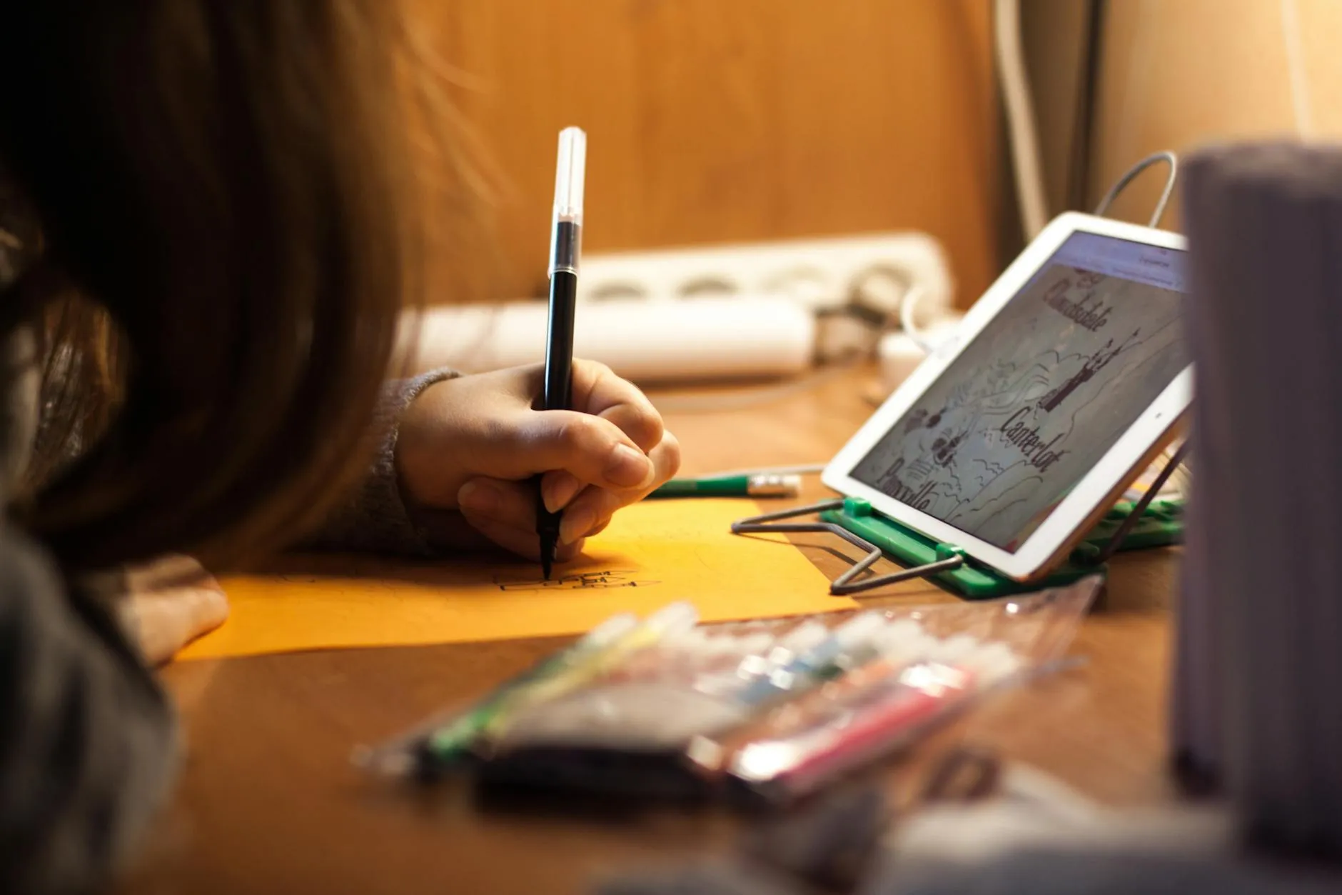 Close up of hands using a tablet to organize study notes on a messy dorm room desk