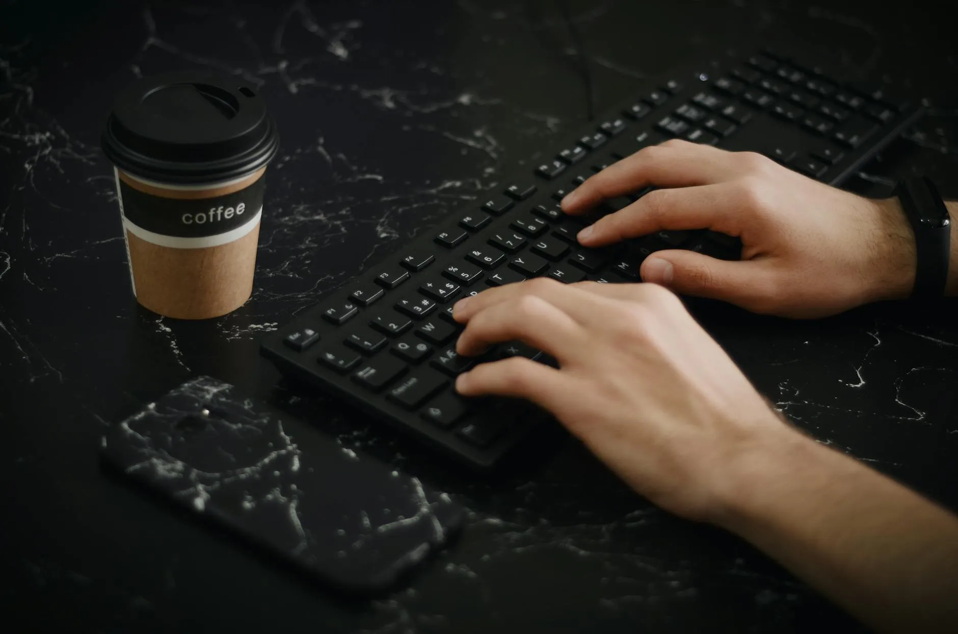 Detail shot of a student typing on a laptop at a messy dorm desk with coffee