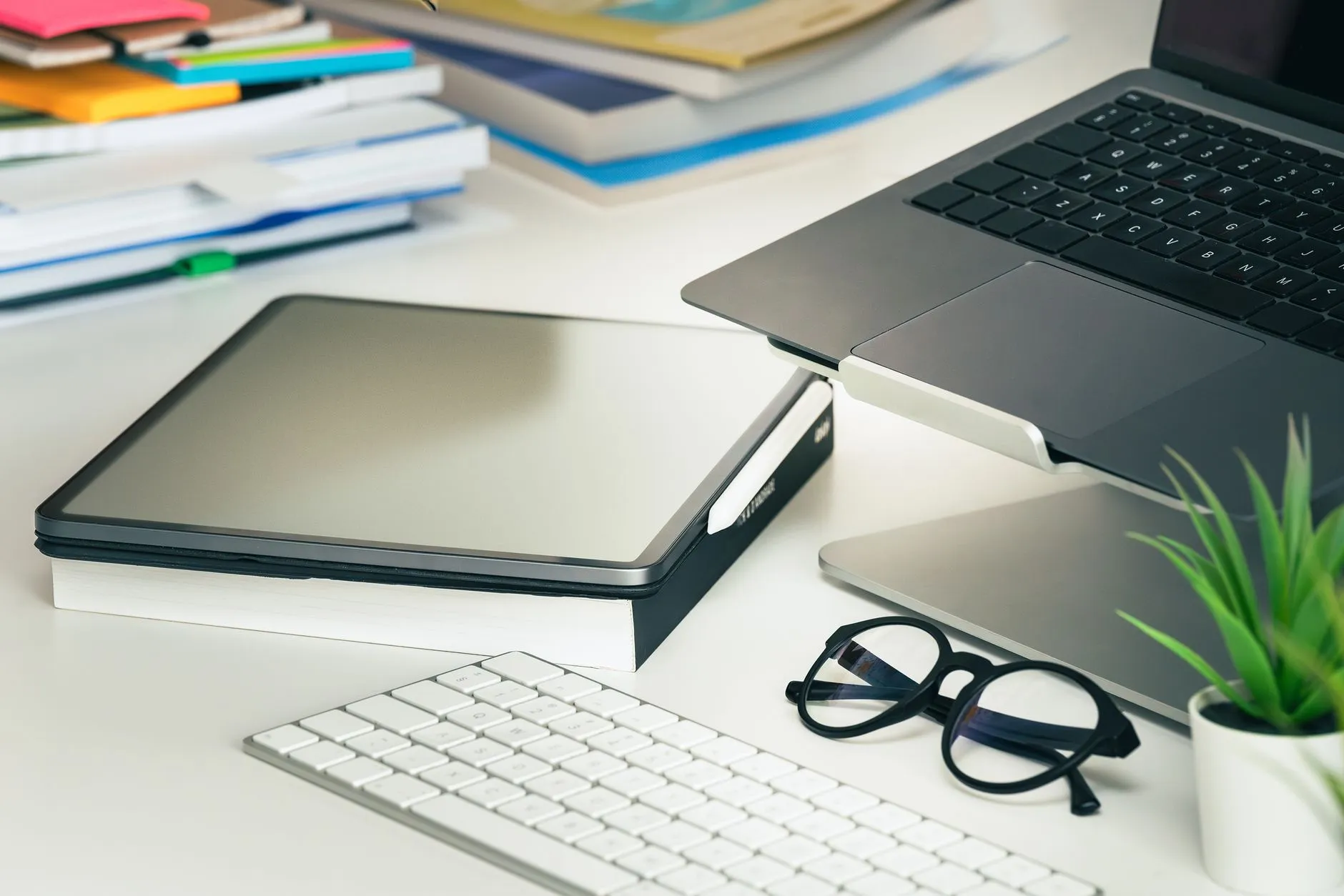 Close up of a student using a tablet to organize digital study notes on a messy dorm room desk