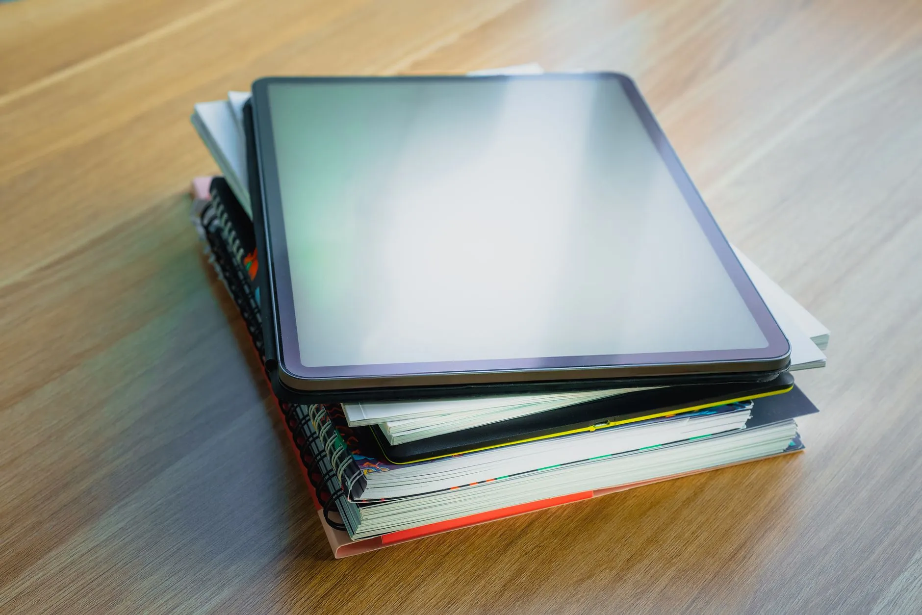 Close up of hands using a tablet to create digital flashcards on a messy dorm room desk