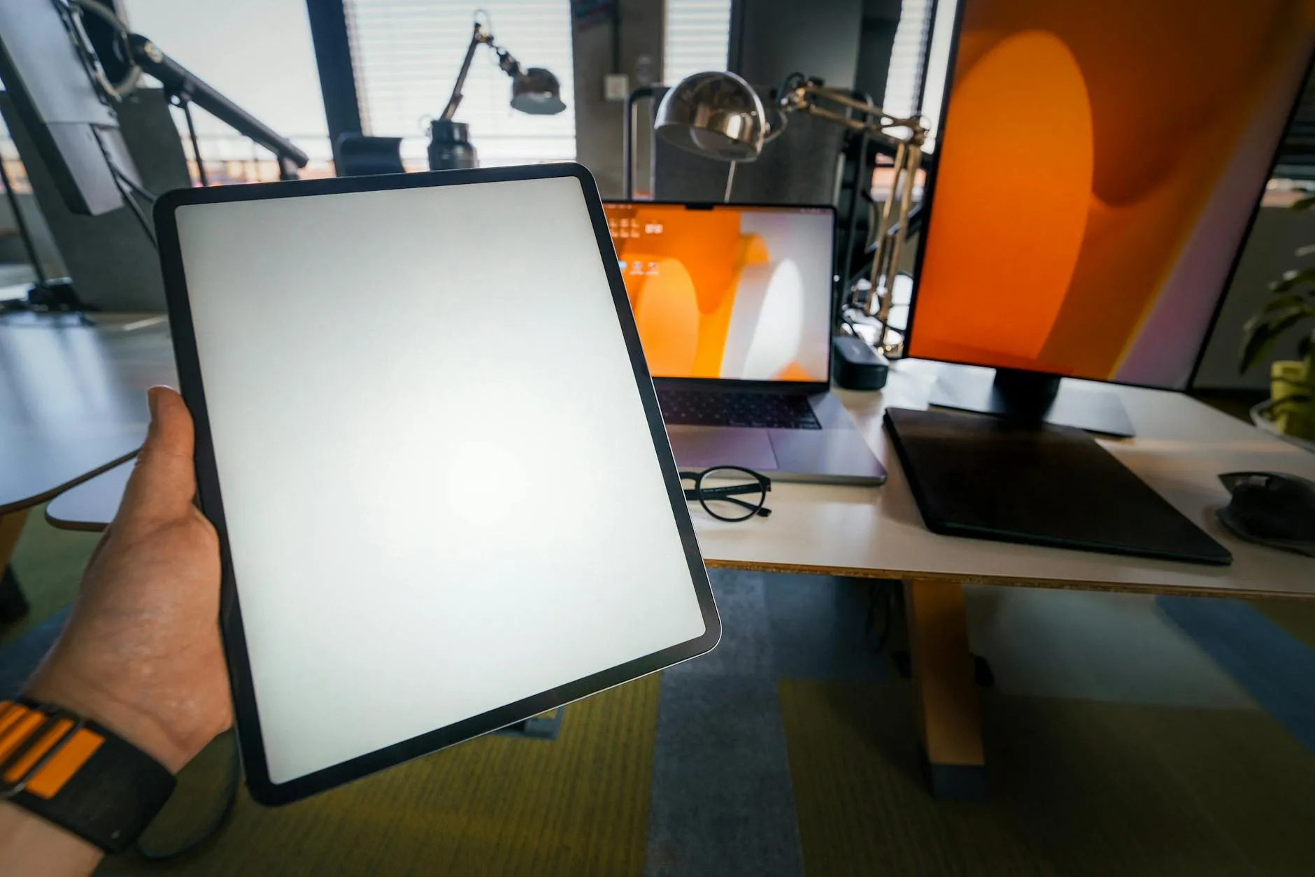 Close-up of student's hands creating digital flashcards on a tablet amidst a messy dorm desk.