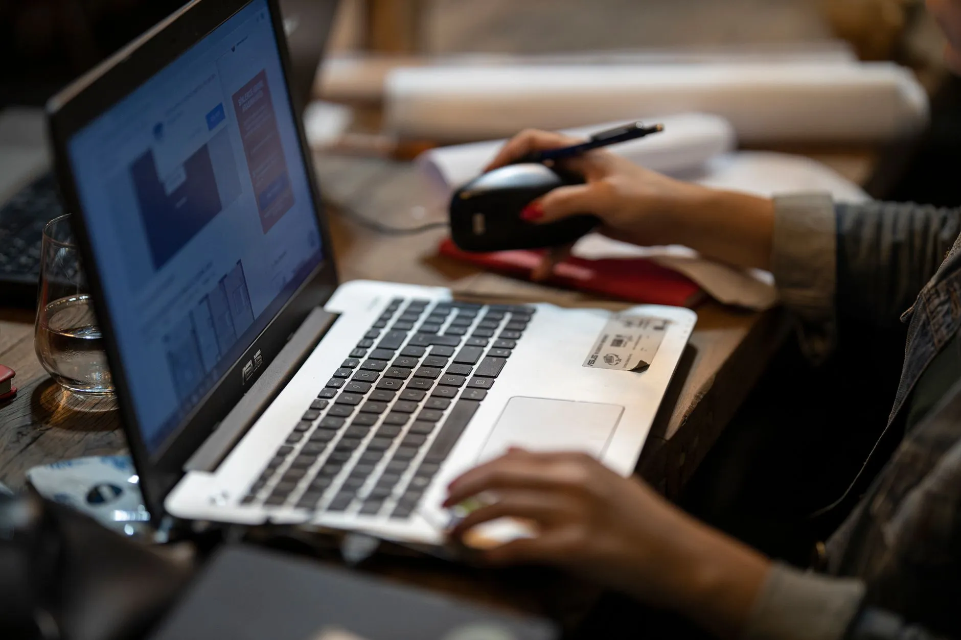Close up of hands typing on a laptop keyboard with educational slides visible on the screen