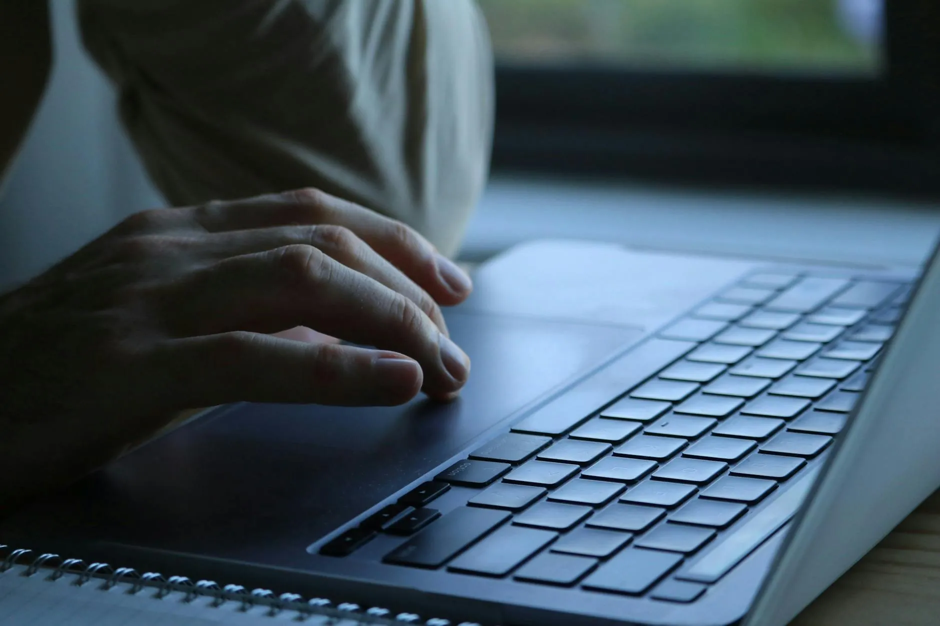 A student using a laptop and a notebook to break down study tasks in a modern university library