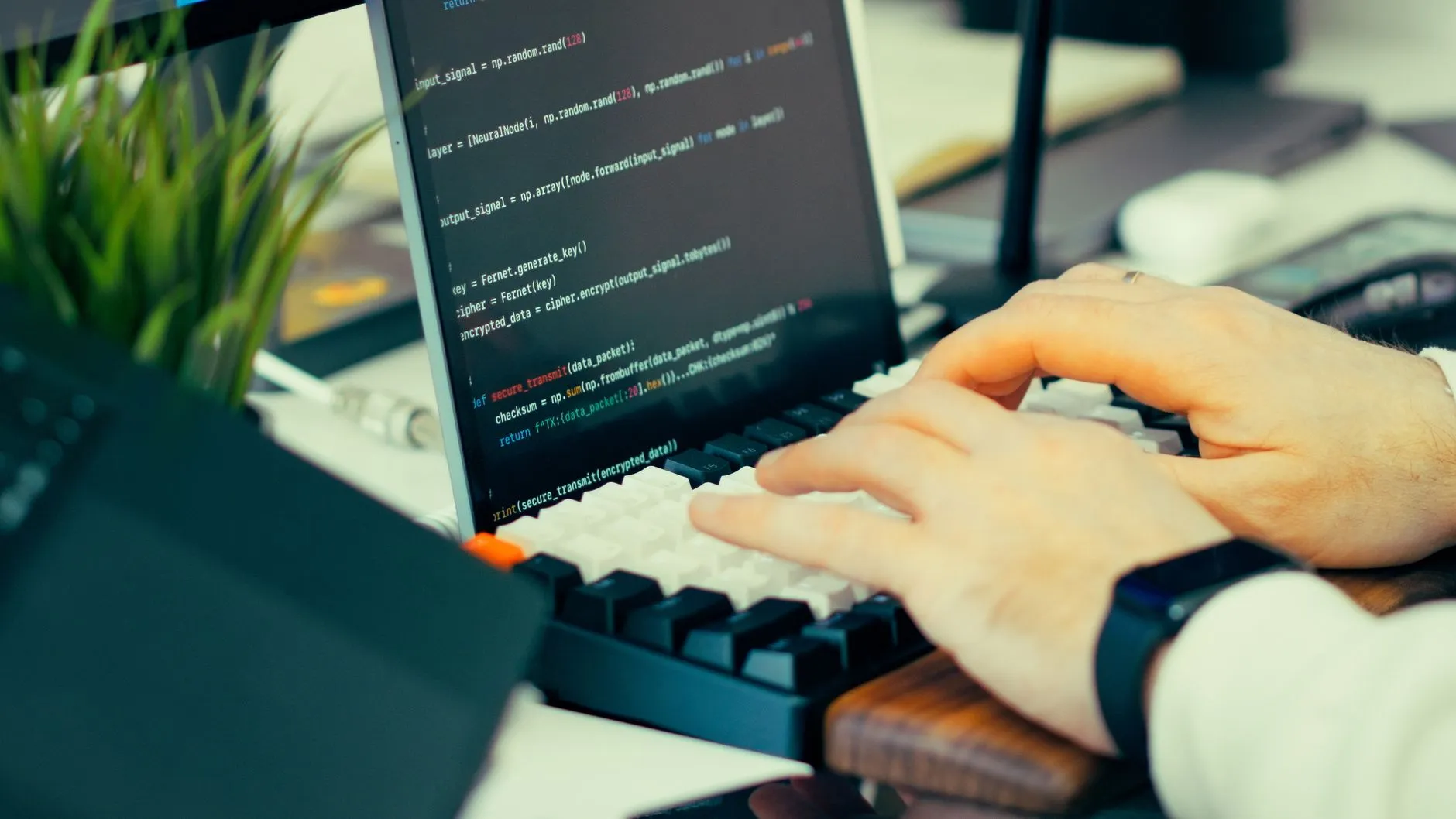 Close up of hands typing on a laptop keyboard on a messy student desk with a coffee cup and notebooks