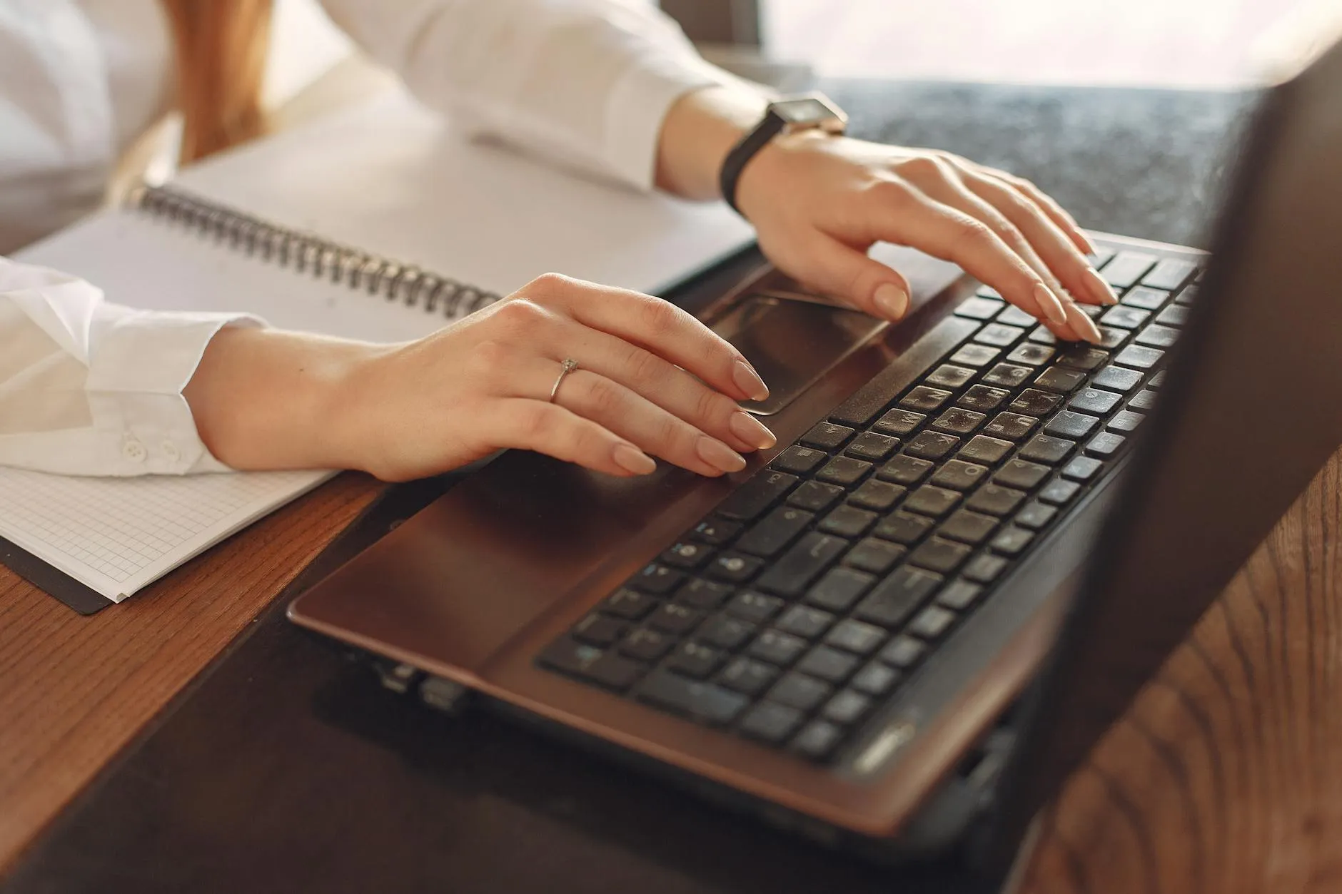 Detailed shot of a student taking notes and using a laptop in a cozy dorm room setting