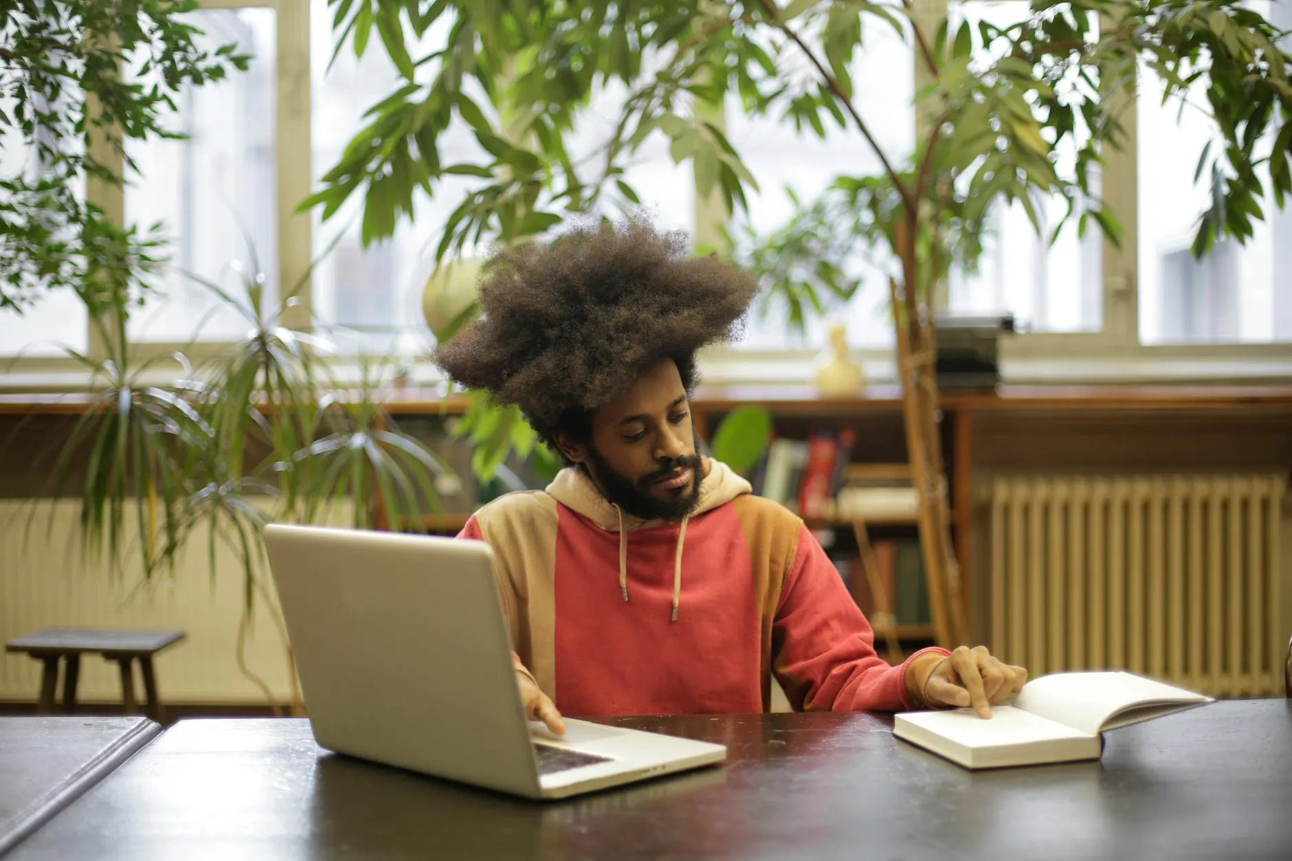 A focused Gen Z student studying on a laptop in a modern library during golden hour, demonstrating productive screen use.