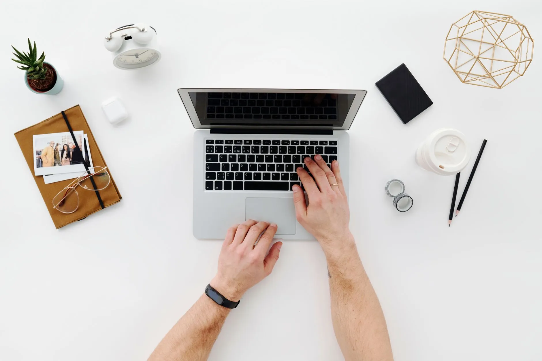 Close up of hands typing on a laptop on a messy student dorm desk with a coffee cup