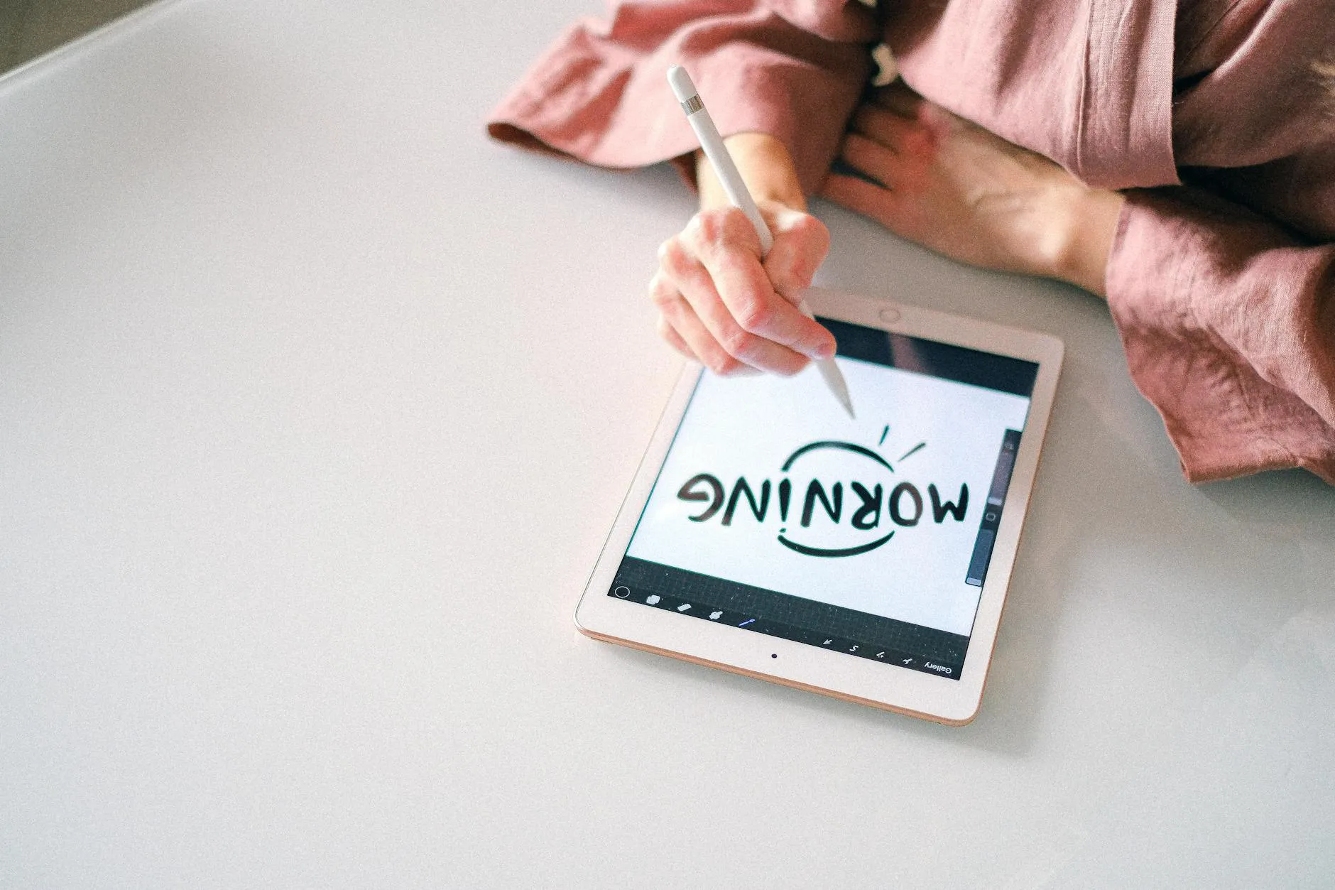 Close-up of student's hands interacting with a tablet, generating notes on a messy dorm room desk.