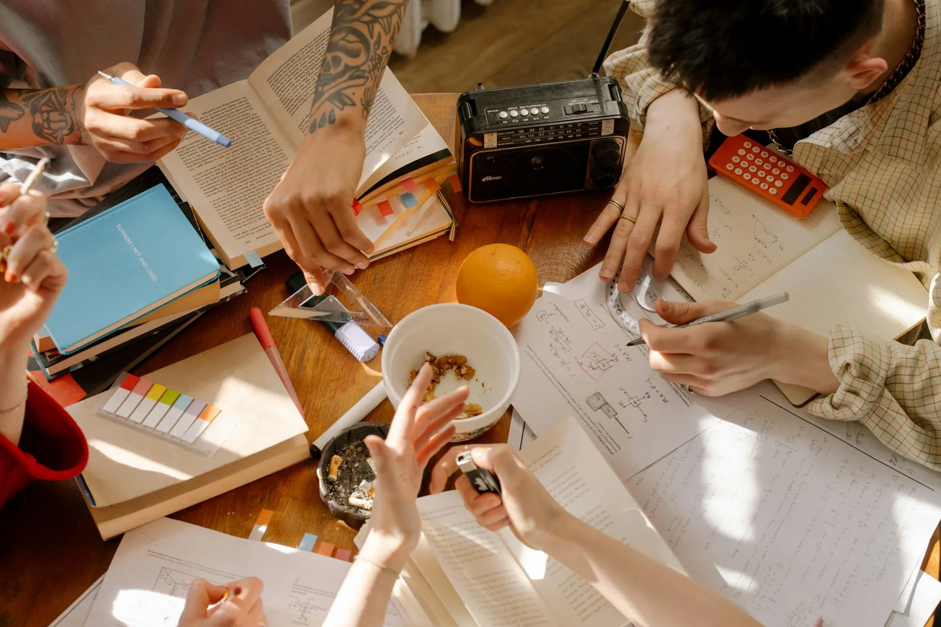 Close up of student hands using a tablet to study with flashcards on a messy dorm room desk
