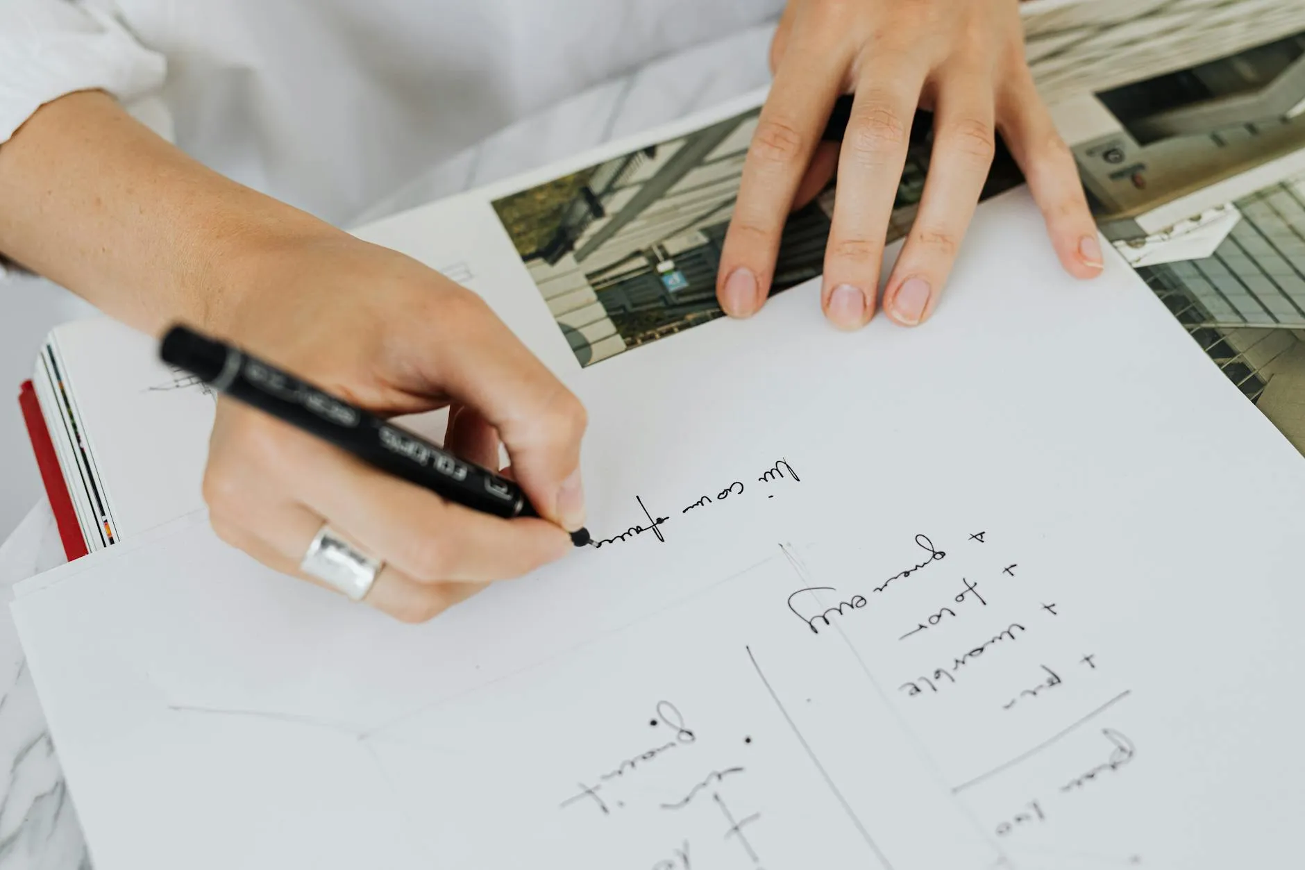 Detailed shot of a student's hands organizing notes into cues and summaries on a messy desk