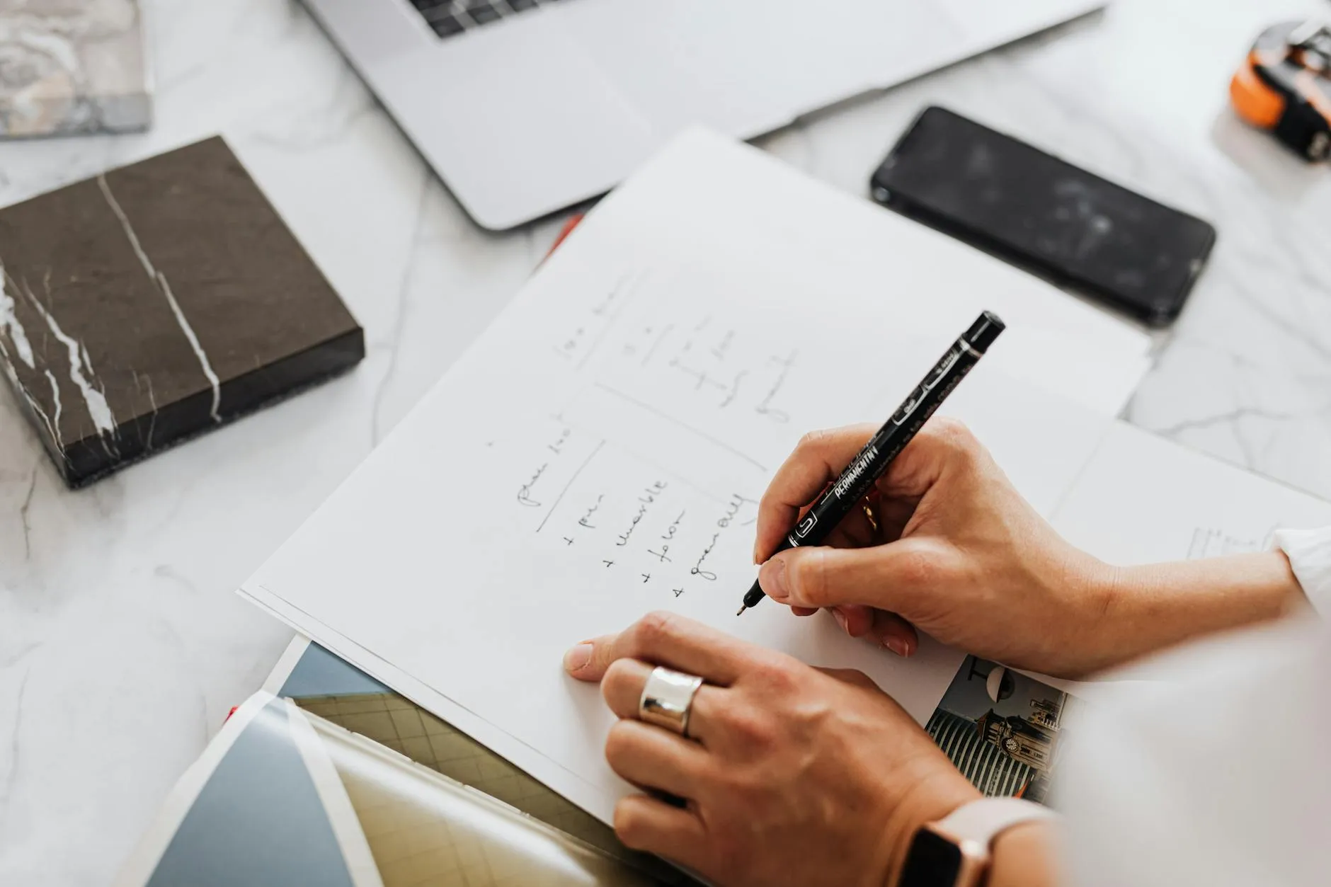 Close-up of a student's hands organizing and linking Zettelkasten notes on a cluttered desk