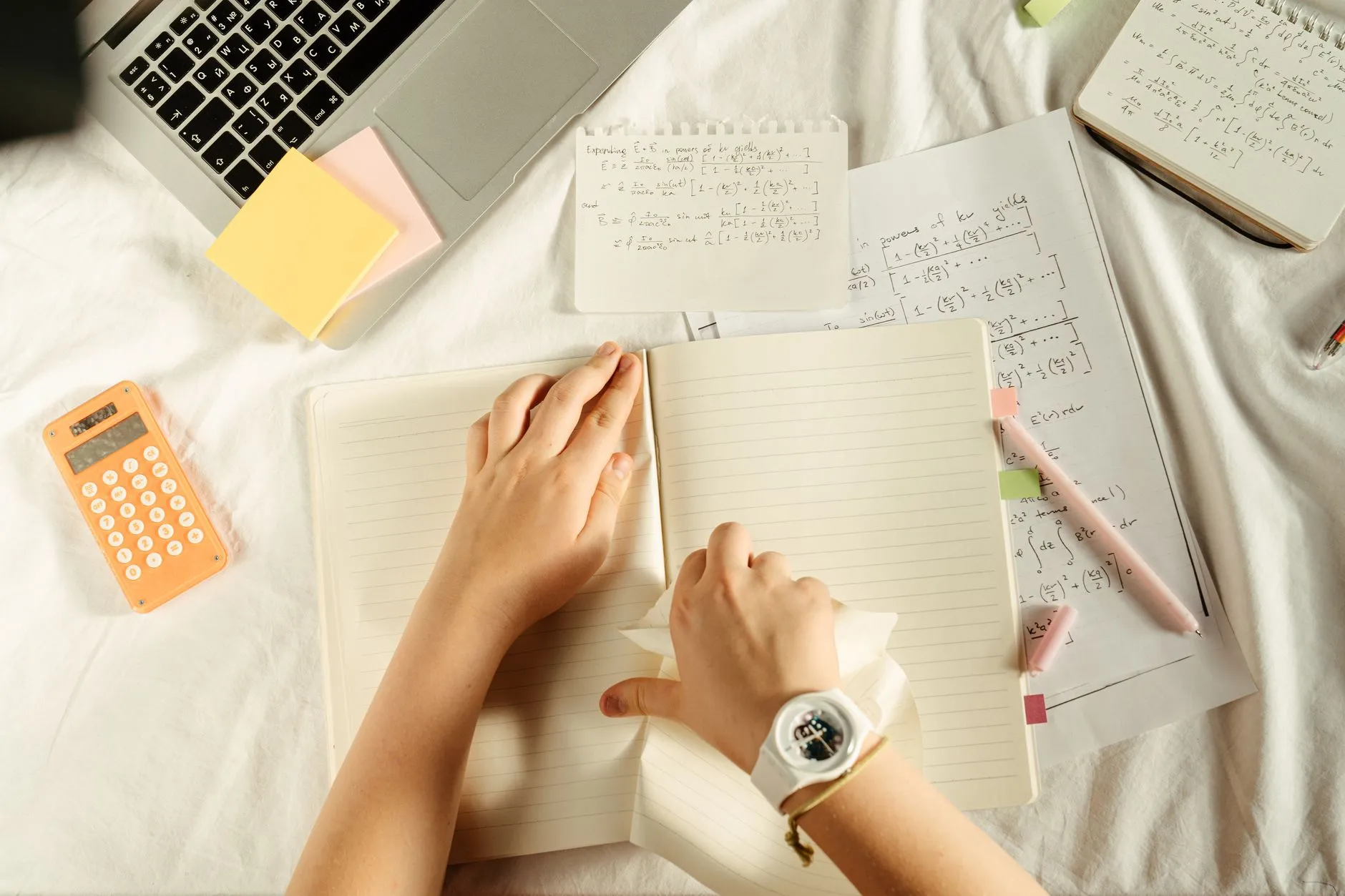 Close up of student hands organizing digital flashcards on a tablet at a messy wooden dorm desk