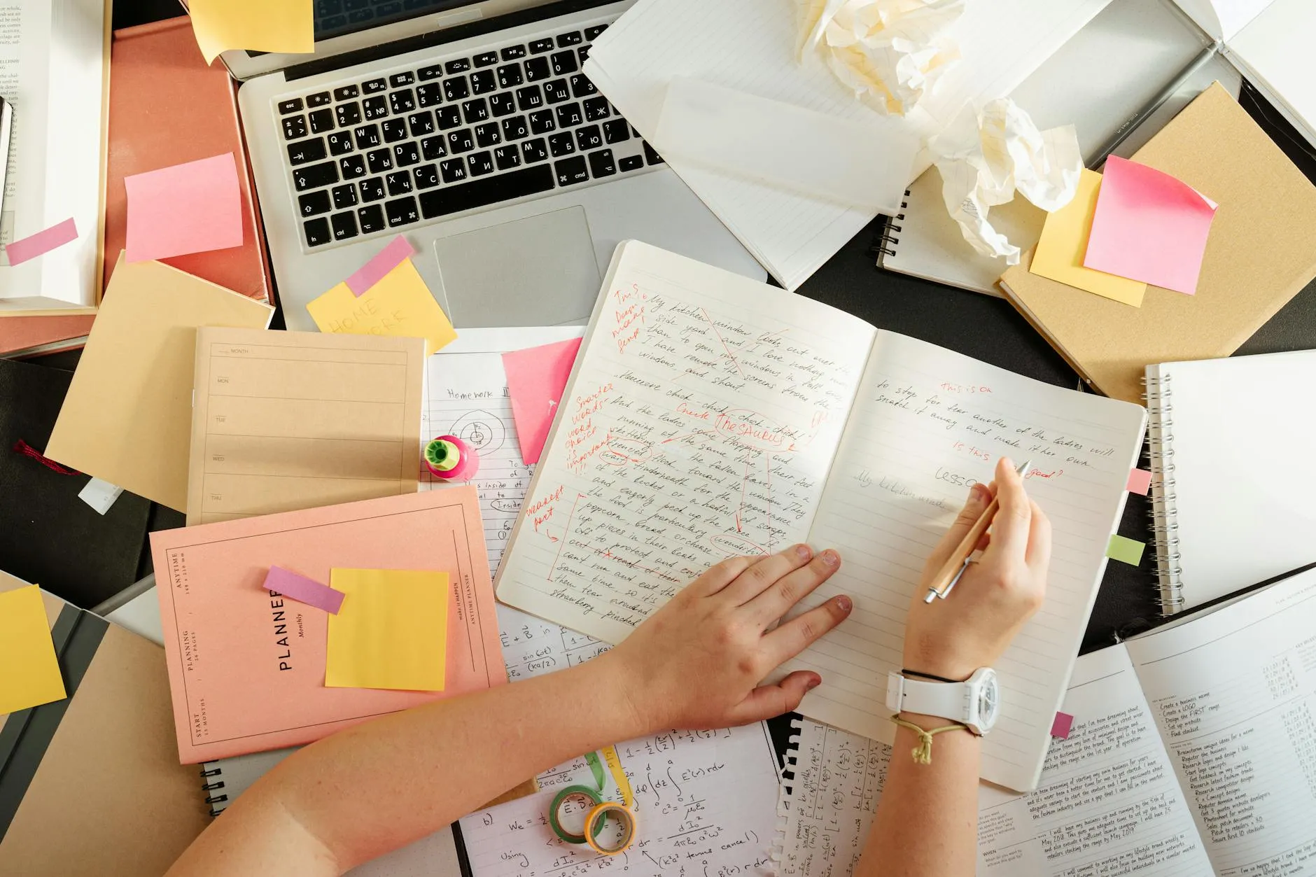 Close up of a student hands using a tablet to generate study notes on a messy university desk