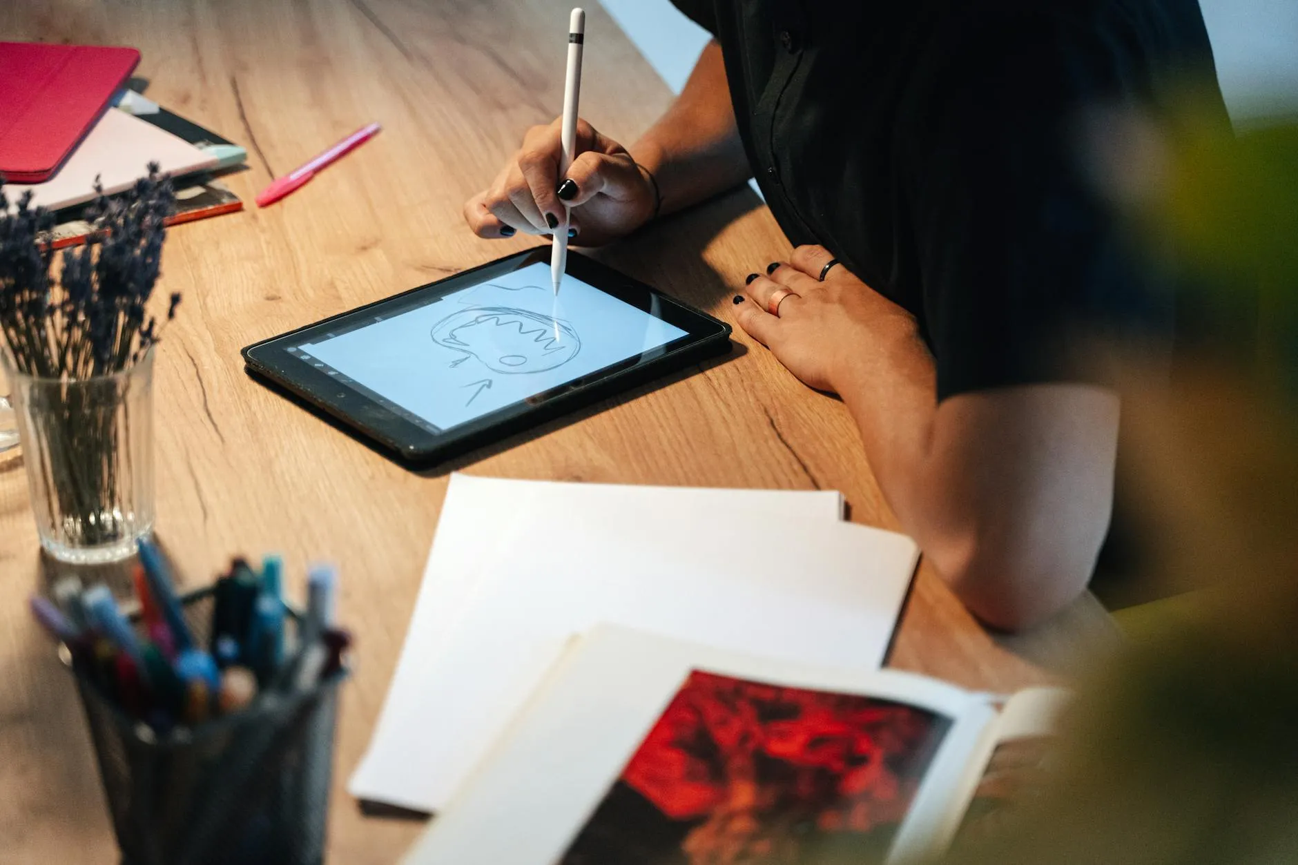 Close up of a student using a tablet and stylus to review notes on a messy desk with a lamp