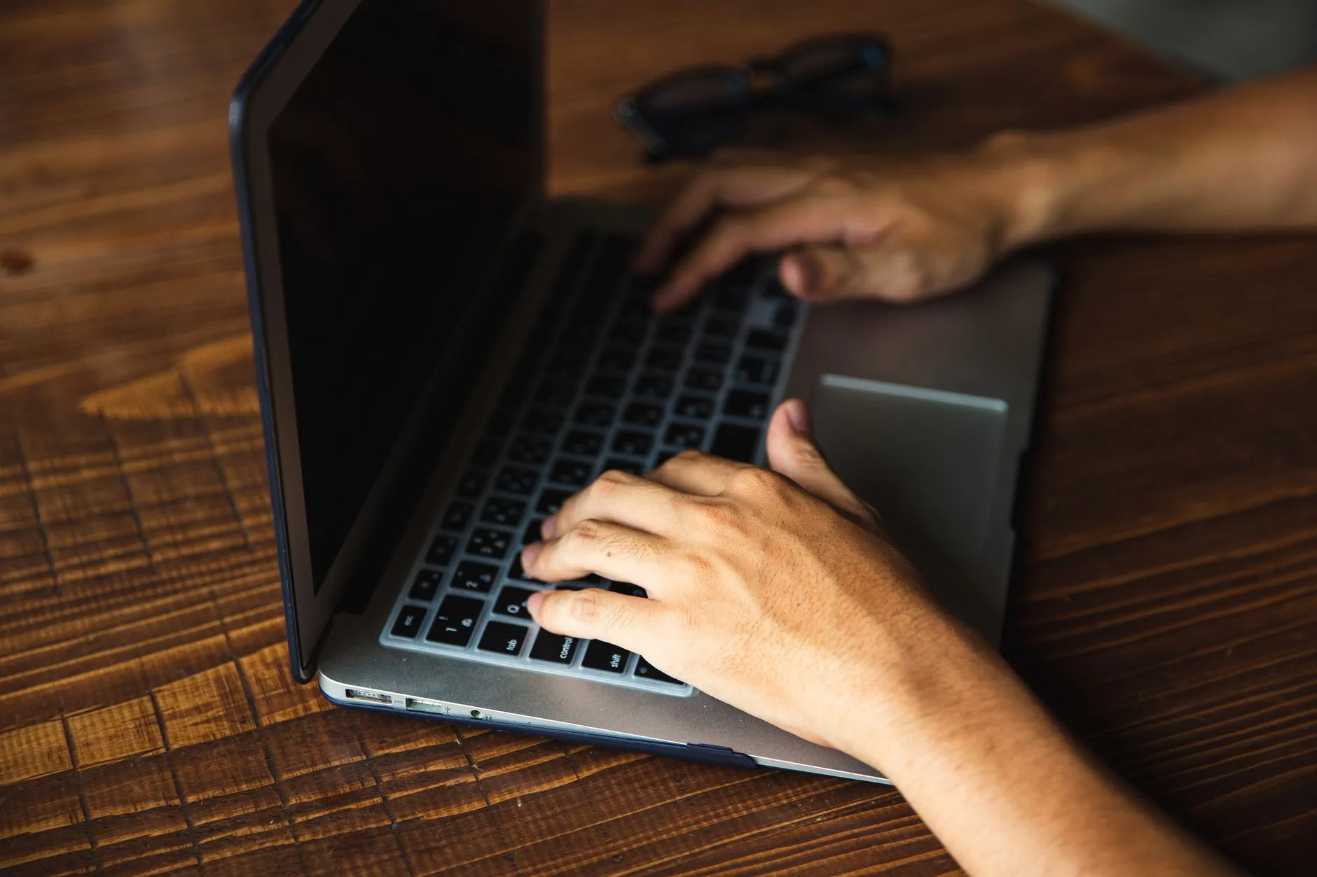 Close up of hands typing on a laptop keyboard in a university library during blue hour