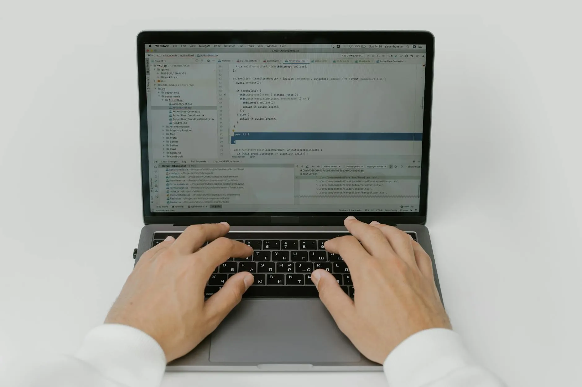 Close-up of student's hands typing on a laptop, with Grammarly interface visible on screen, on a messy dorm desk