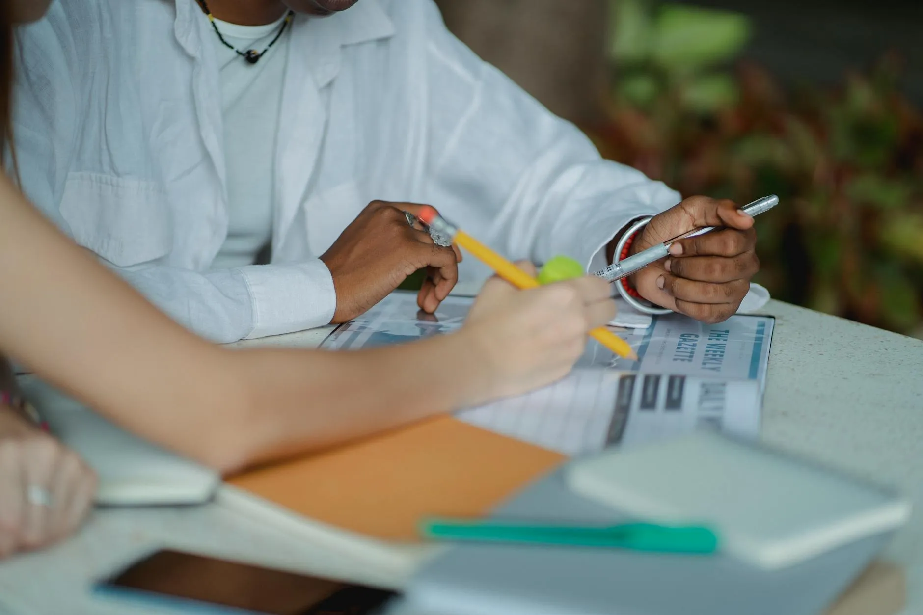 Close up of student hands typing on a tablet surrounded by notebooks and coffee