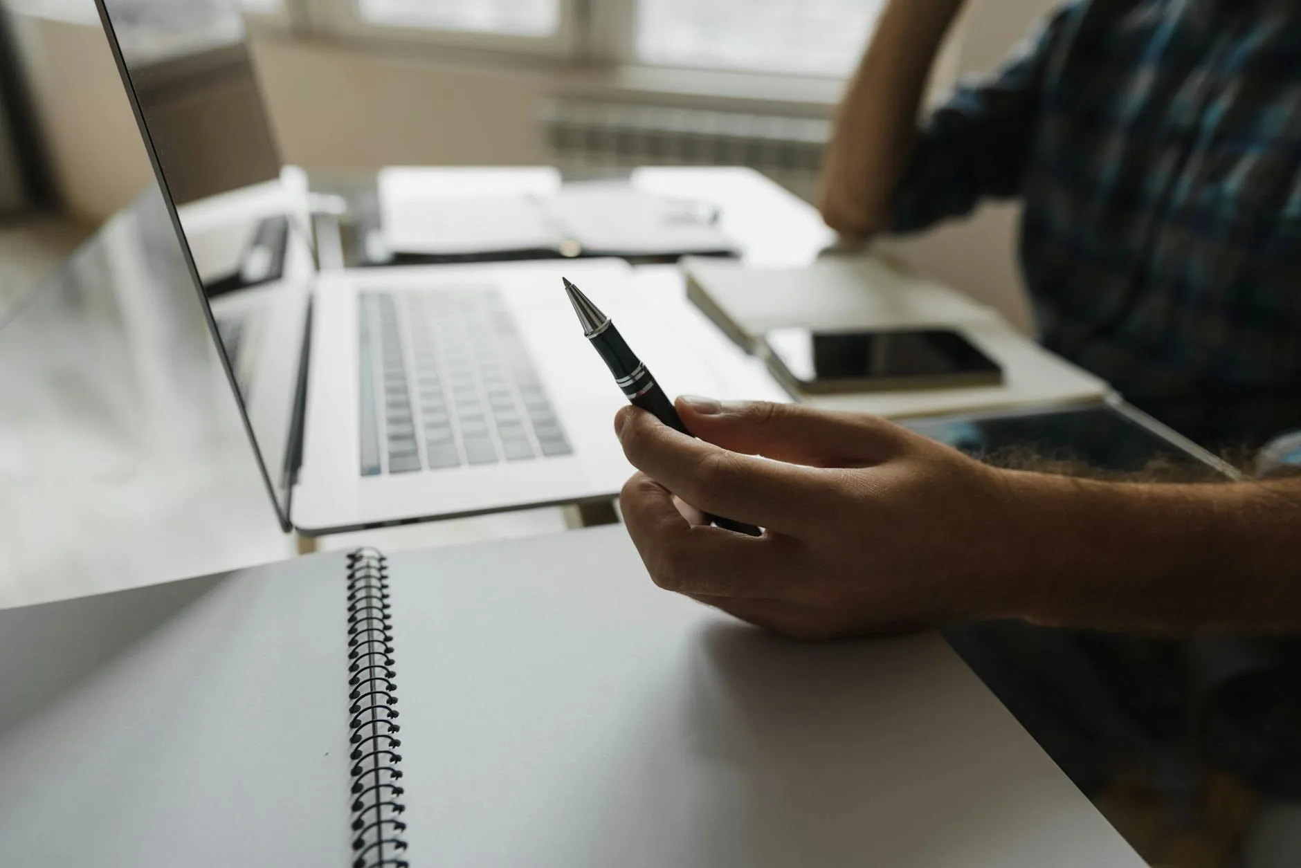 Close-up of student's hands creating digital flashcards on a tablet at a messy desk