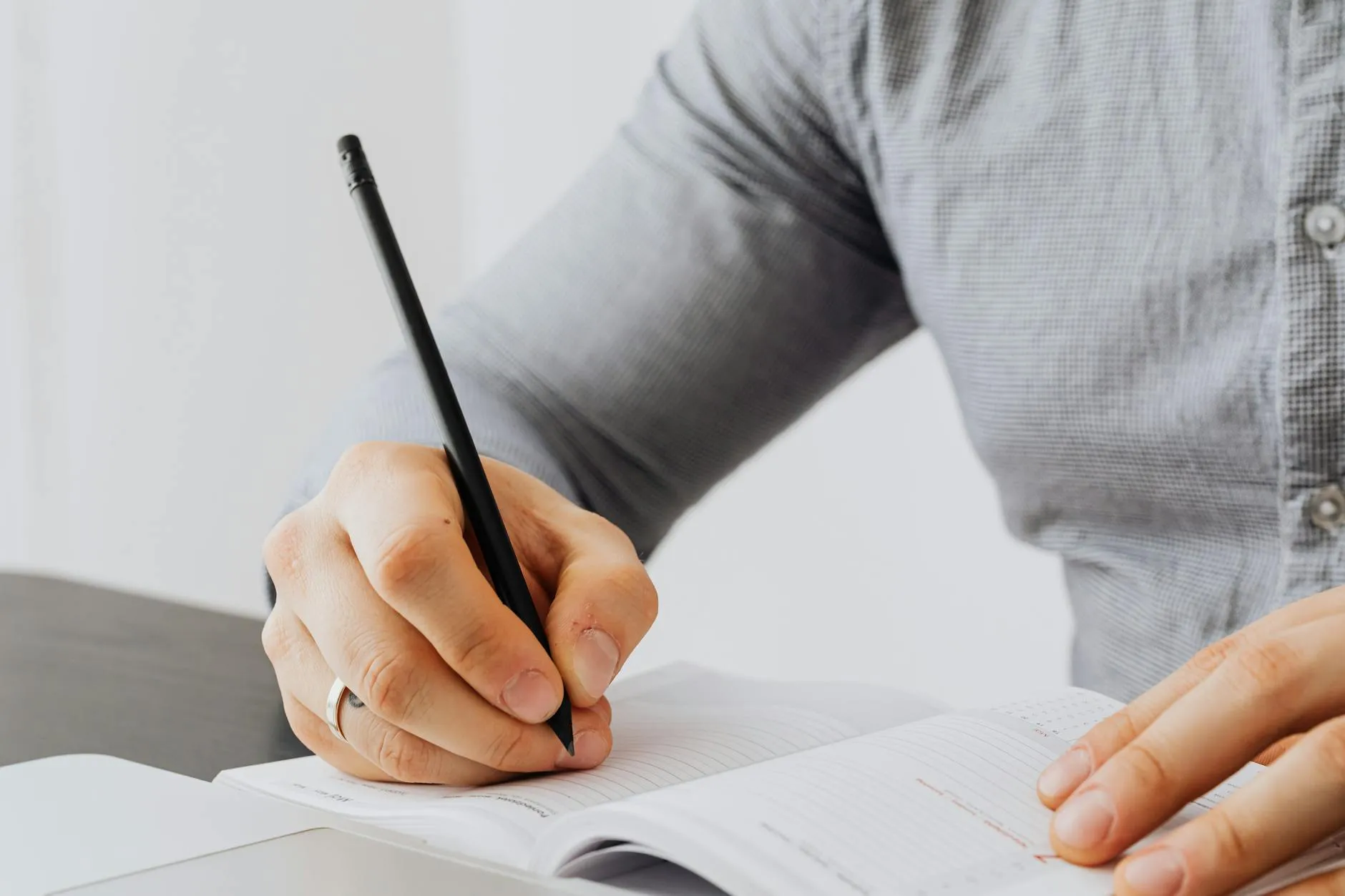 Close up of hands writing on a tablet at a messy study desk in a cozy dorm room