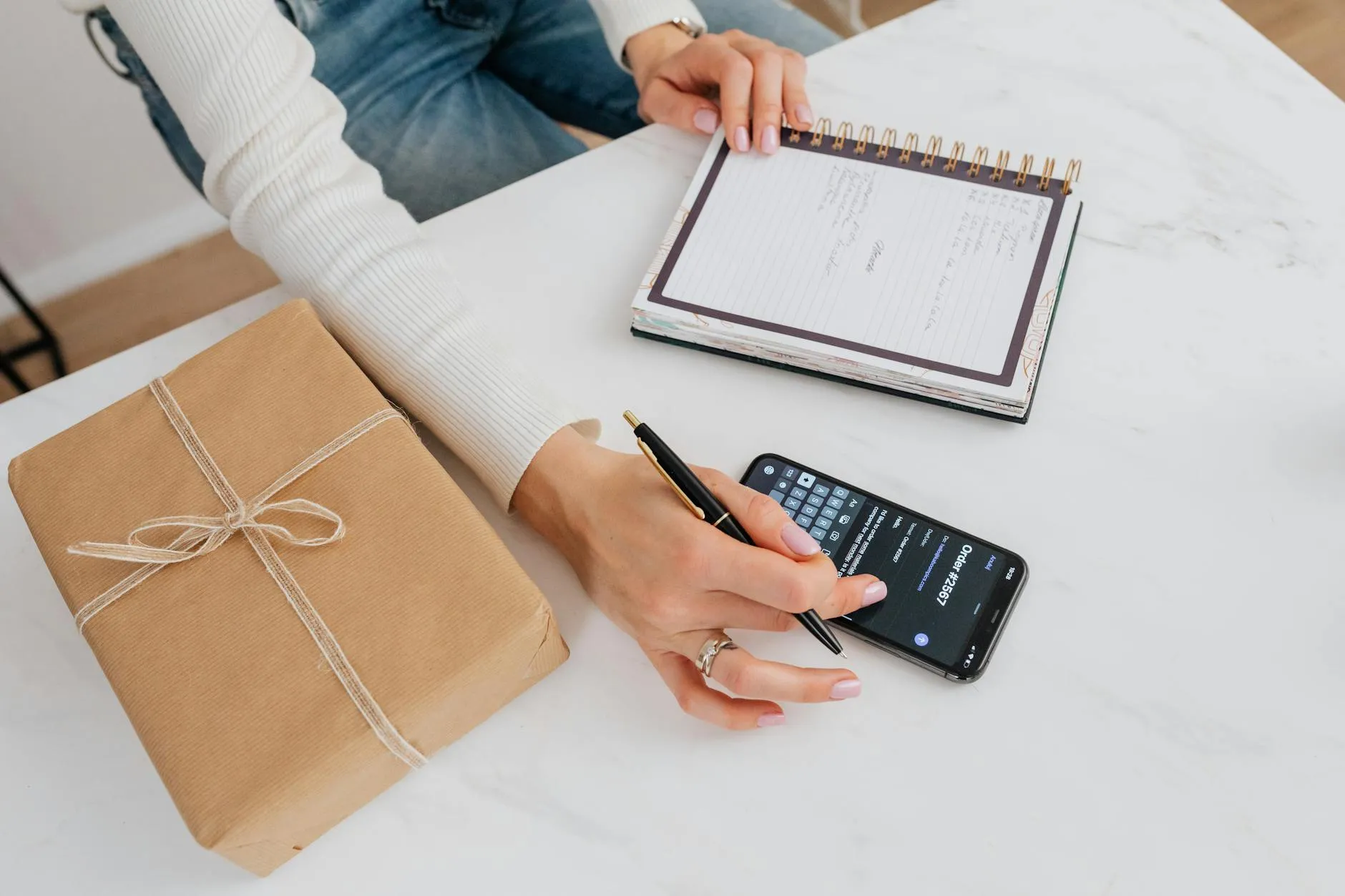Close-up of a student's hands efficiently creating digital flashcards on a tablet amidst a slightly messy study desk.