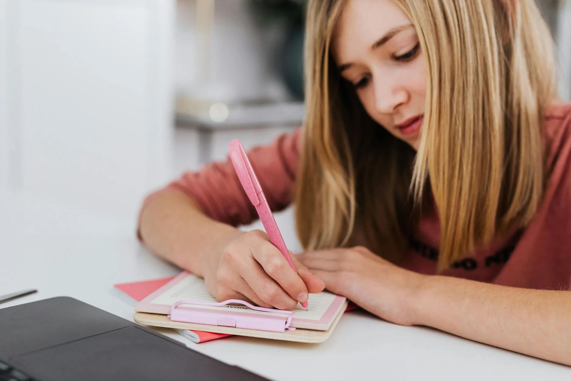 Close-up of a student's hand placing their smartphone face down on a cluttered dorm desk.