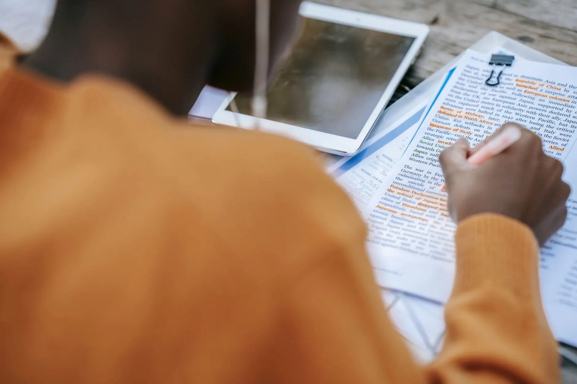 Student with headphones reviewing notes on modern campus