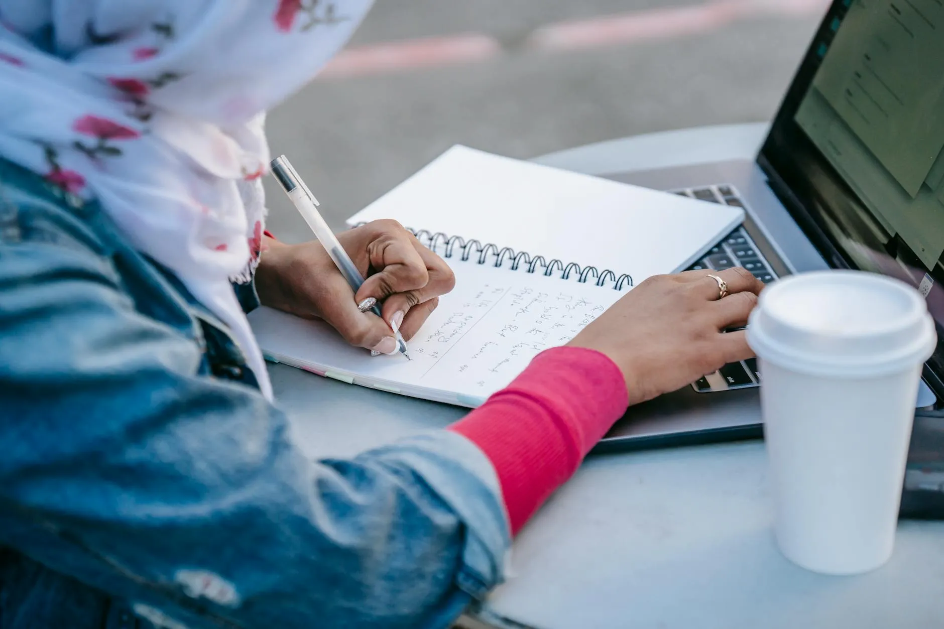 A Gen Z student focused on their laptop with a coffee cup on a slightly messy dorm room desk, illuminated by soft morning light.