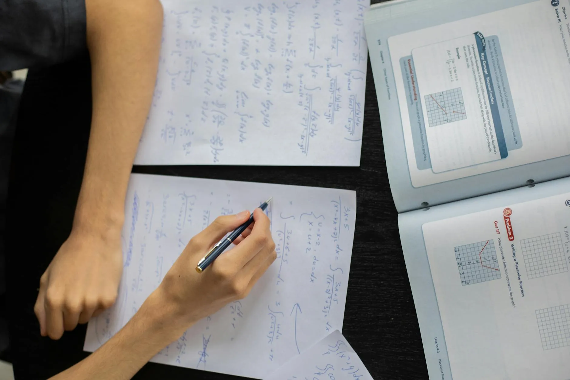 Close-up of a student's hands creating flashcards from a medical textbook on a cluttered dorm desk.