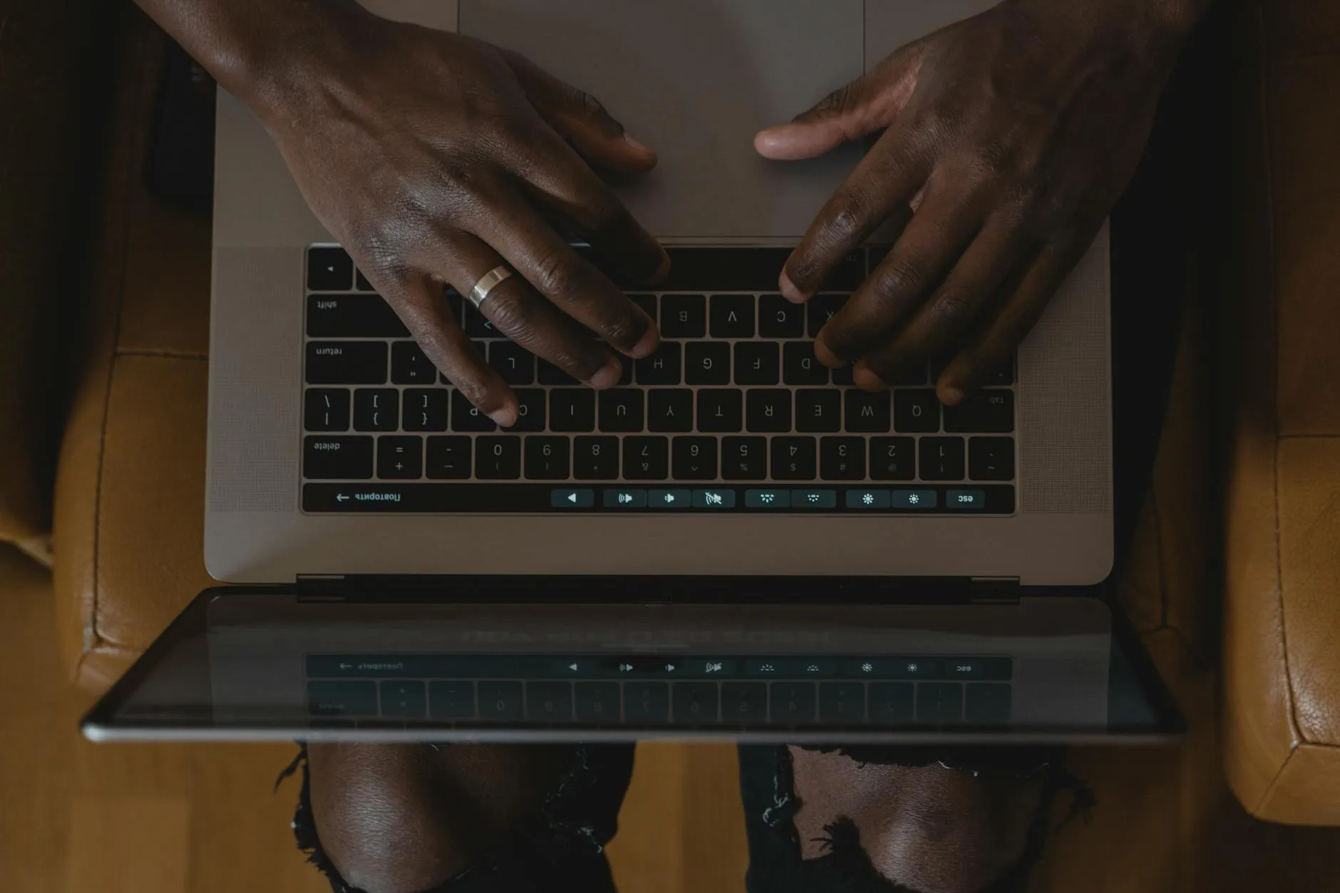 Detail shot of a student typing on a laptop with a coffee cup and notebooks nearby