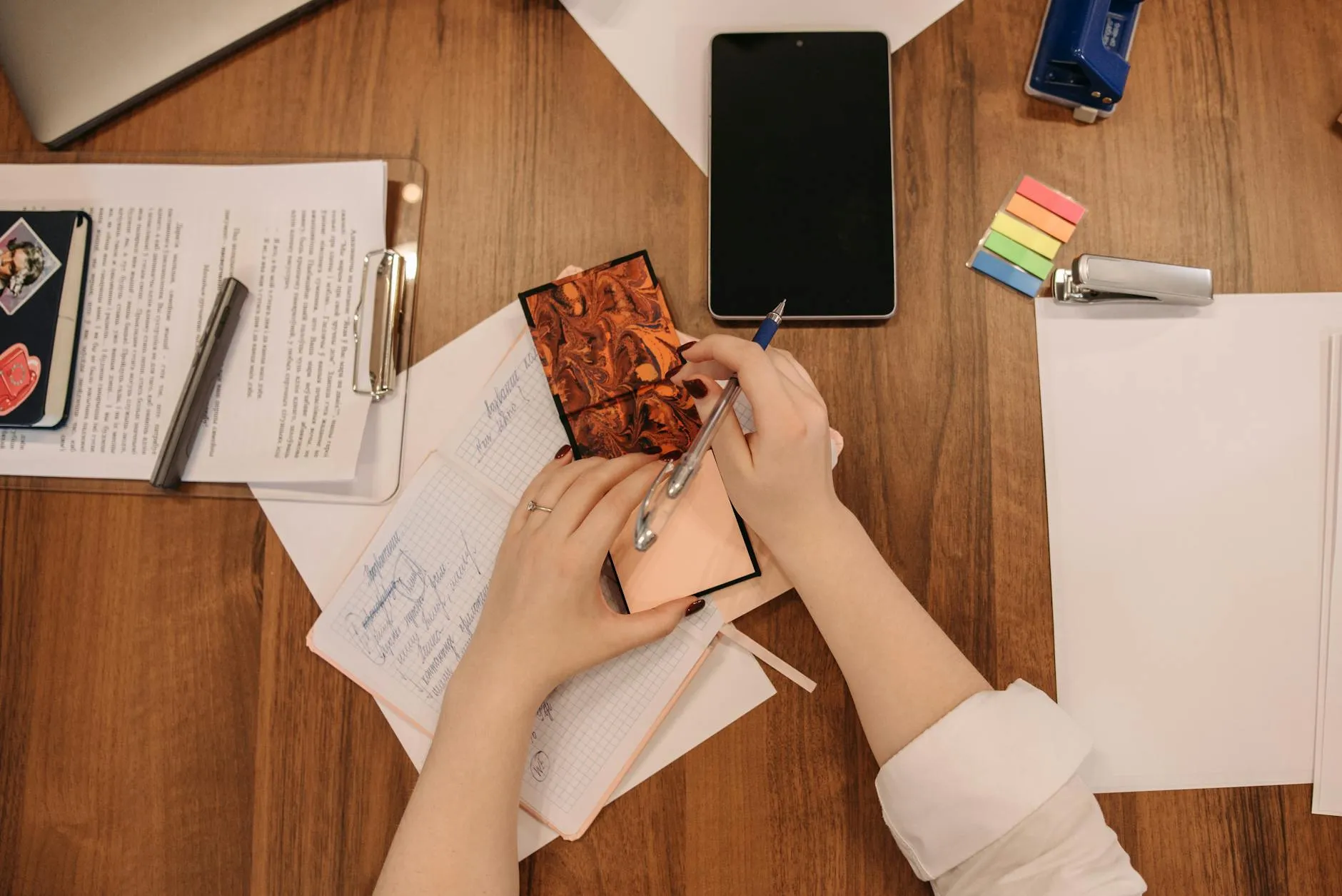 Close up of a student using a tablet to create digital flashcards on a cluttered desk