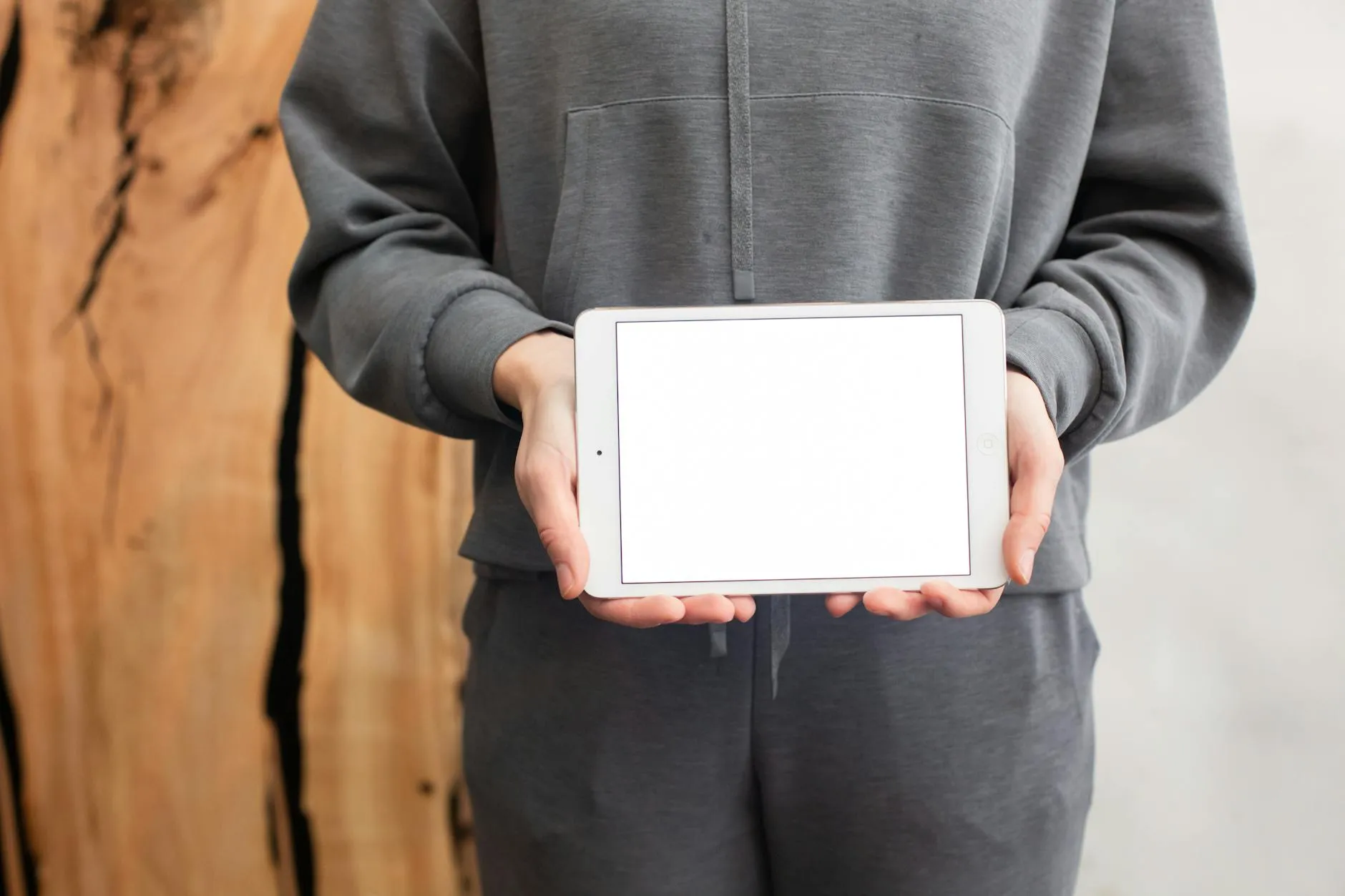 Close-up of a student's hands creating digital flashcards on a tablet, surrounded by scattered notes on a dorm room desk.