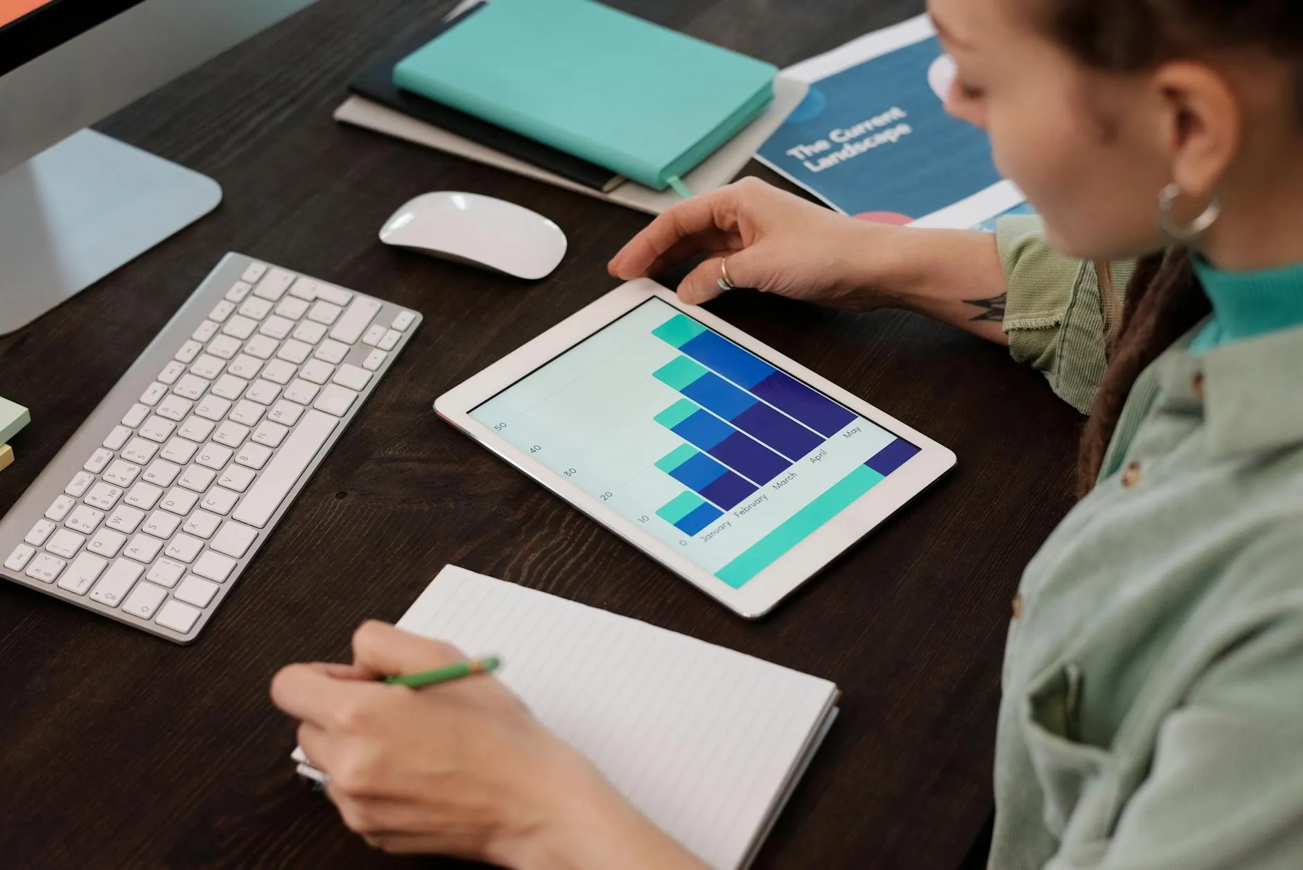 Close up of a student using a tablet and stylus to organize study notes on a messy wooden desk