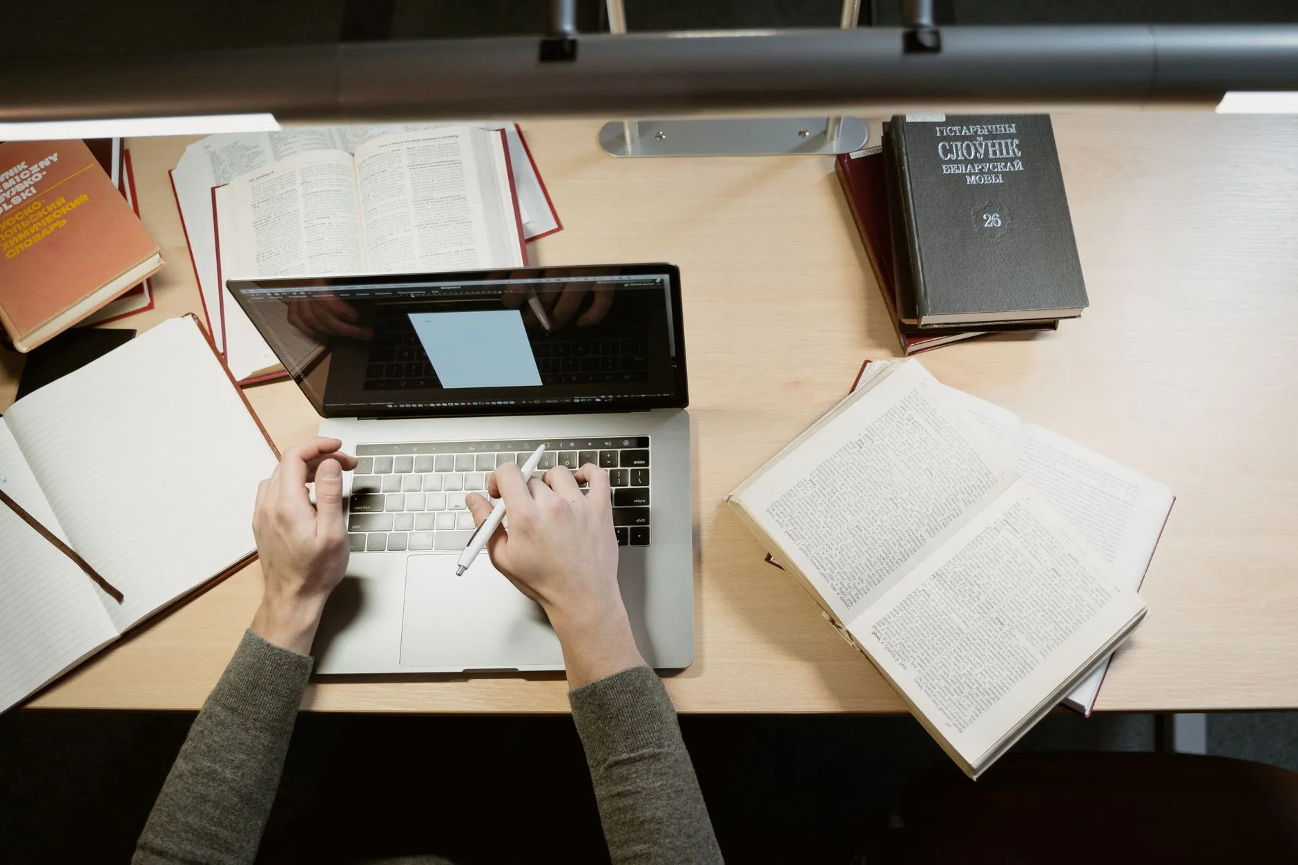 Close up of hands typing on a laptop on a messy college dorm desk with coffee