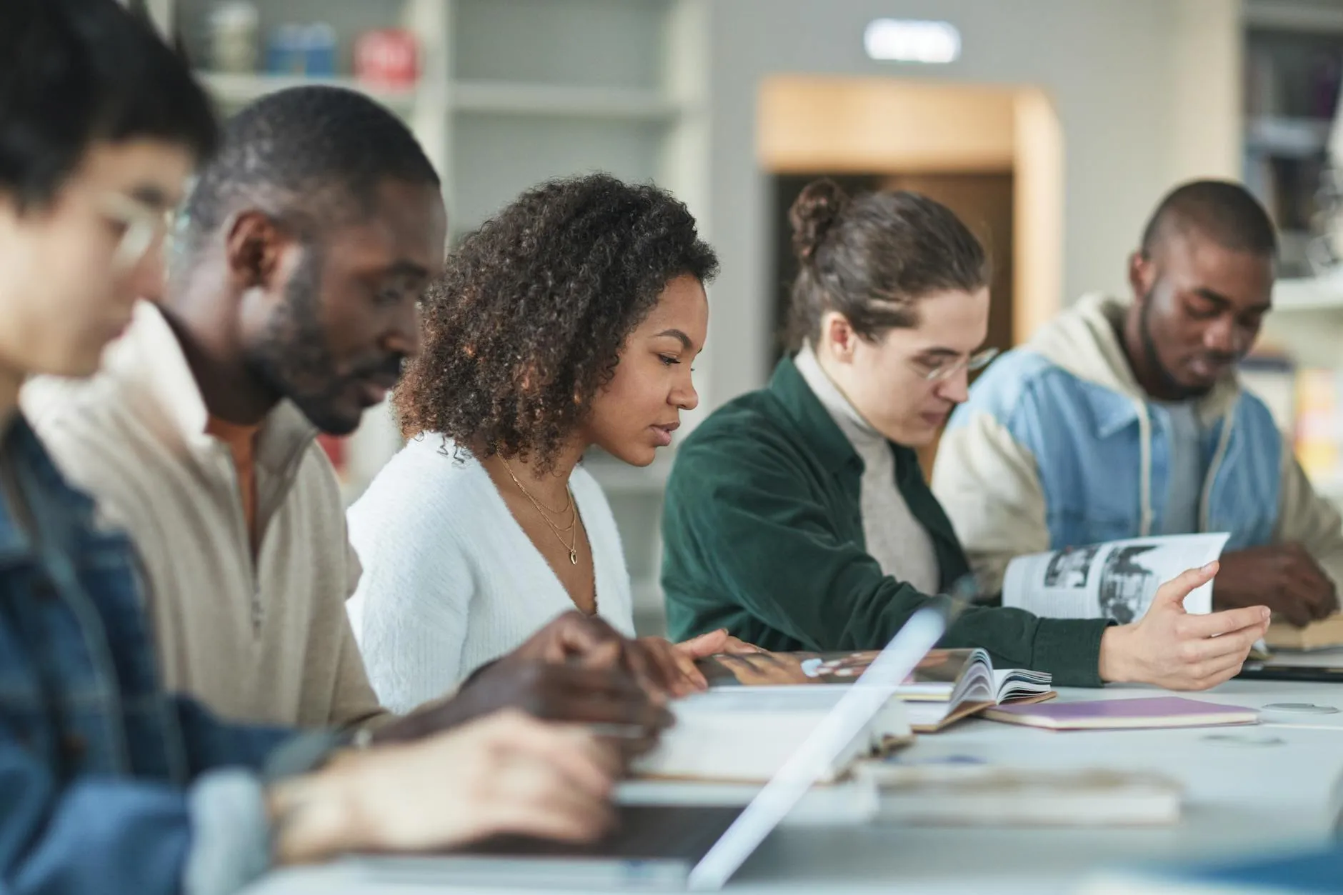 A group of diverse students using laptops and tablets in a modern university library