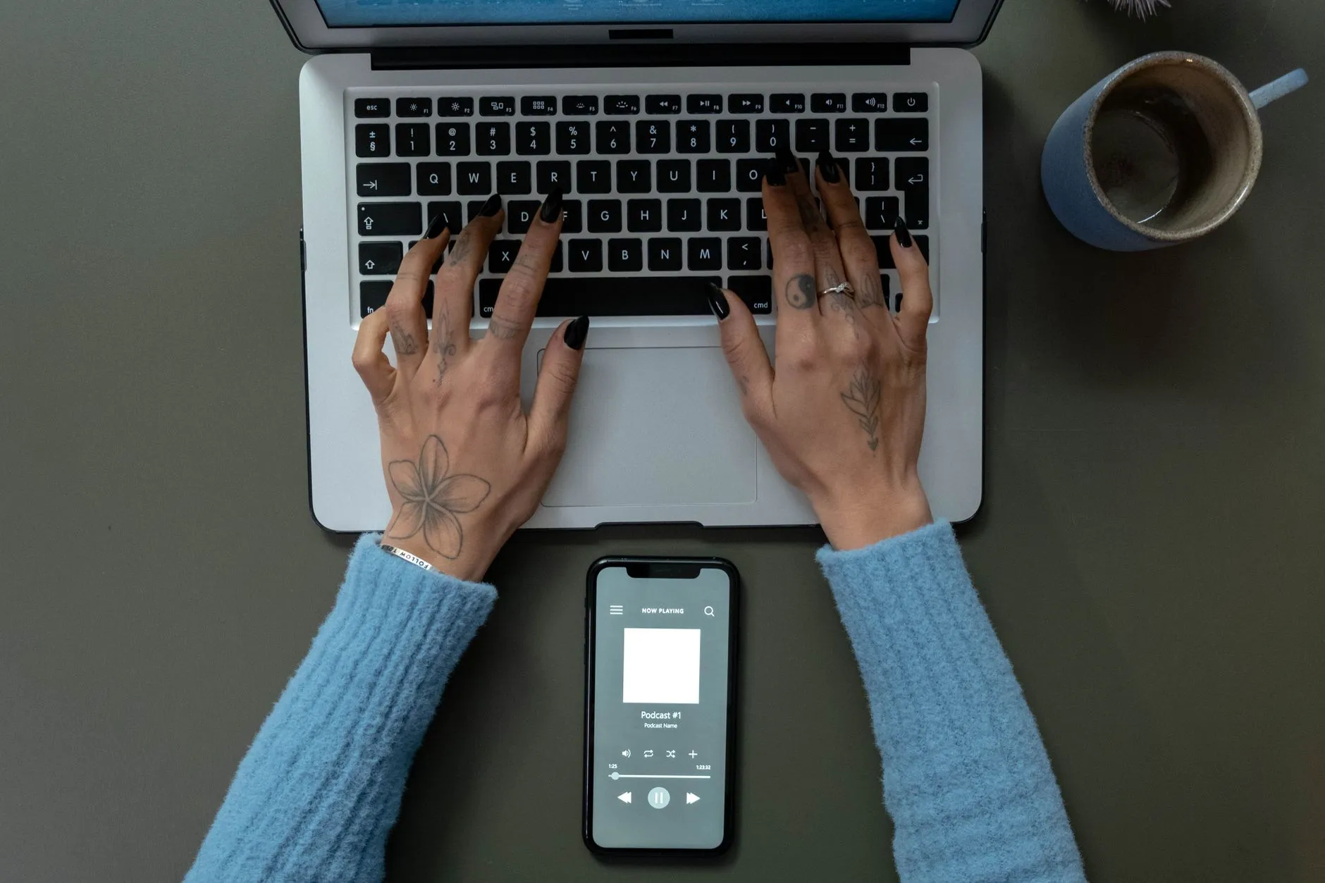 Close up of hands typing on a laptop on a messy dorm desk with a coffee cup