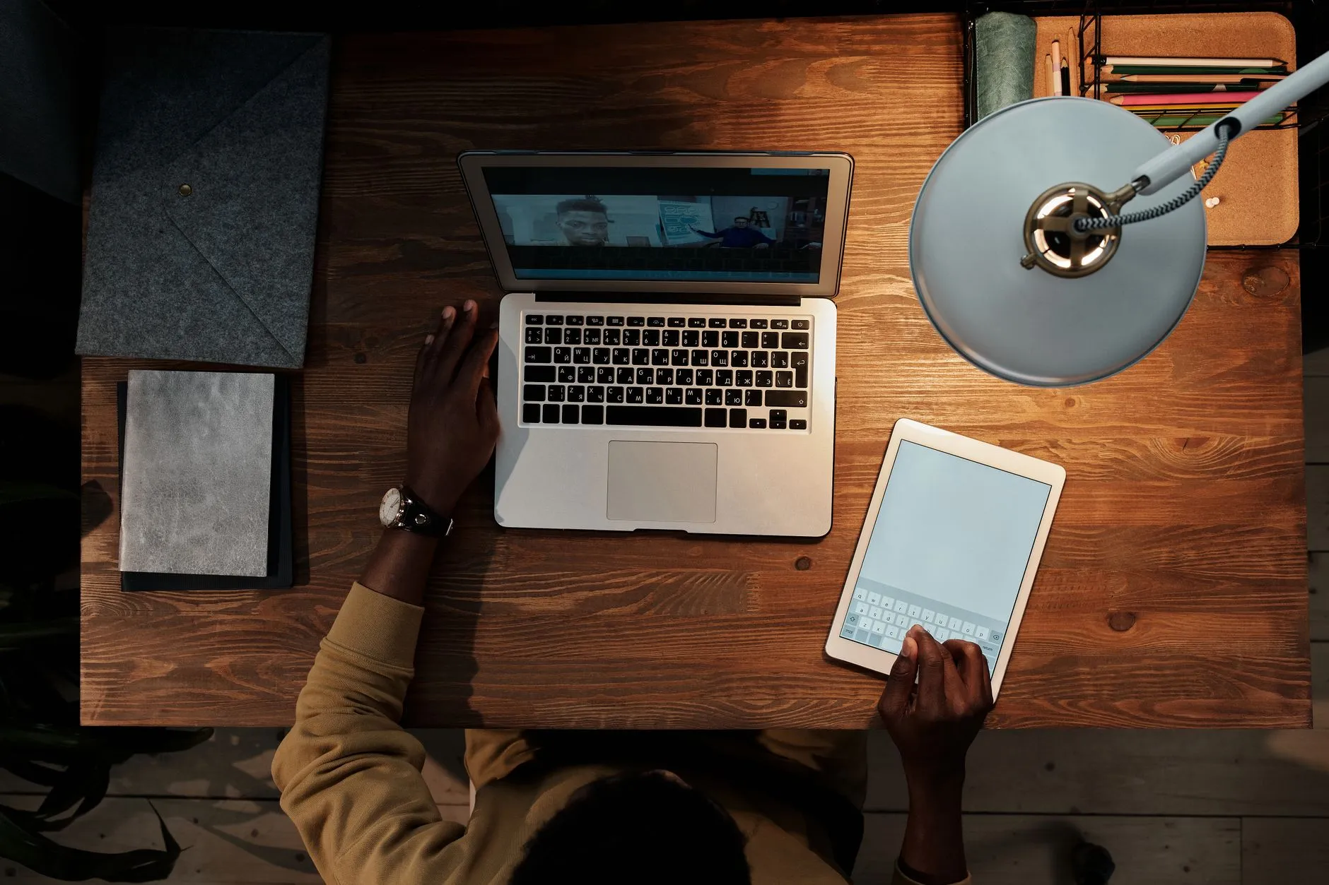 Close up of student hands using a tablet to study on a messy dorm room desk with a laptop