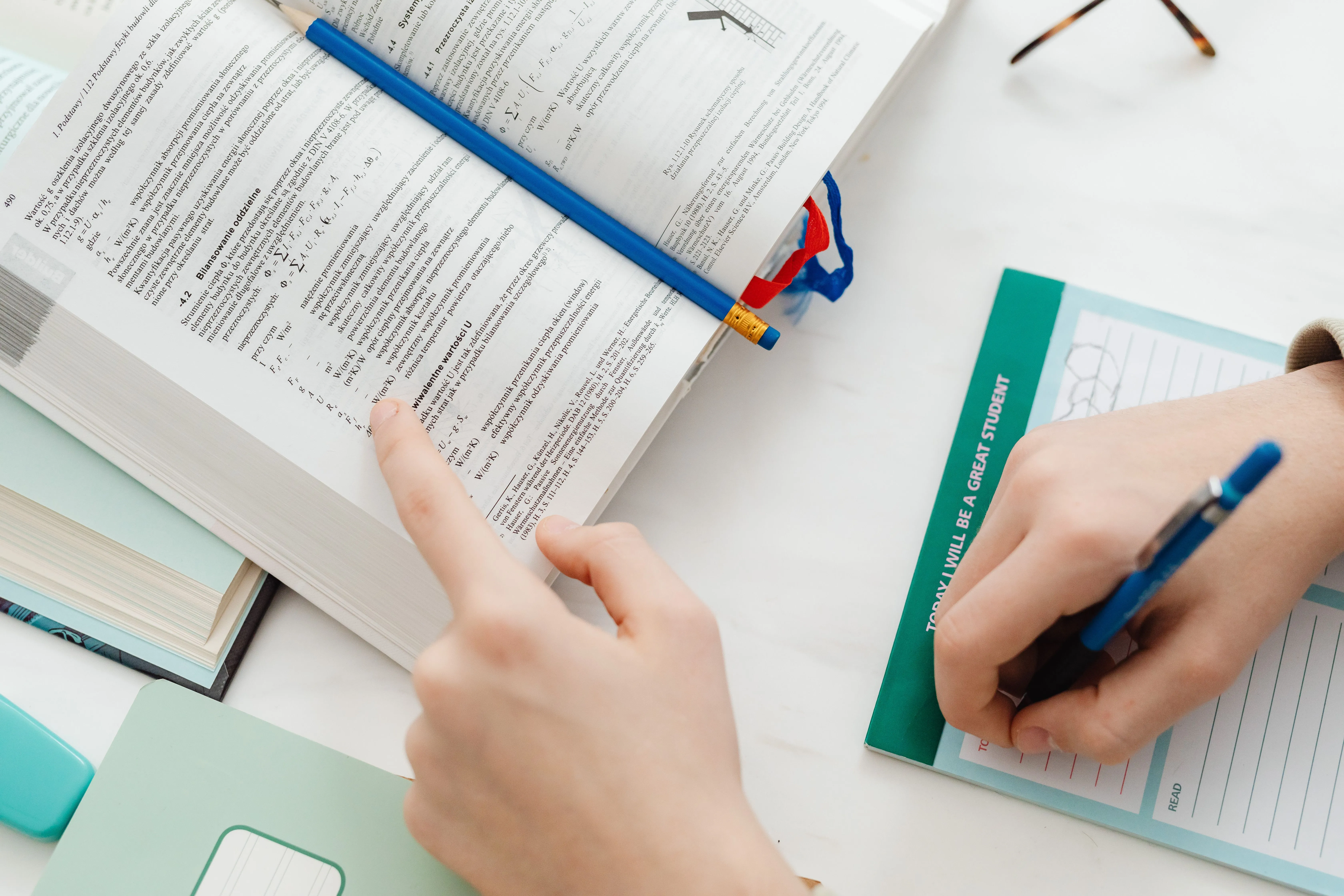 Close-up of a student studying mathematics from an open book with notes on the table.
