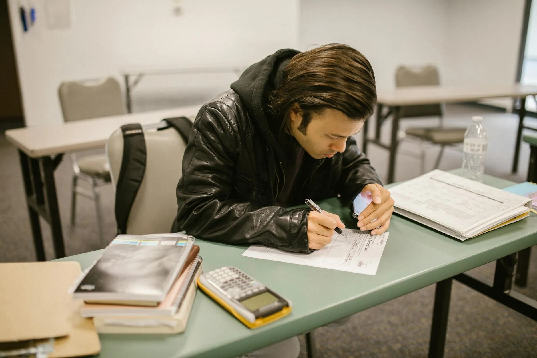 A focused Gen Z student intently writing in a notebook with a pen, their phone conspicuously absent from the desk, symbolizing a successful dopamine detox.